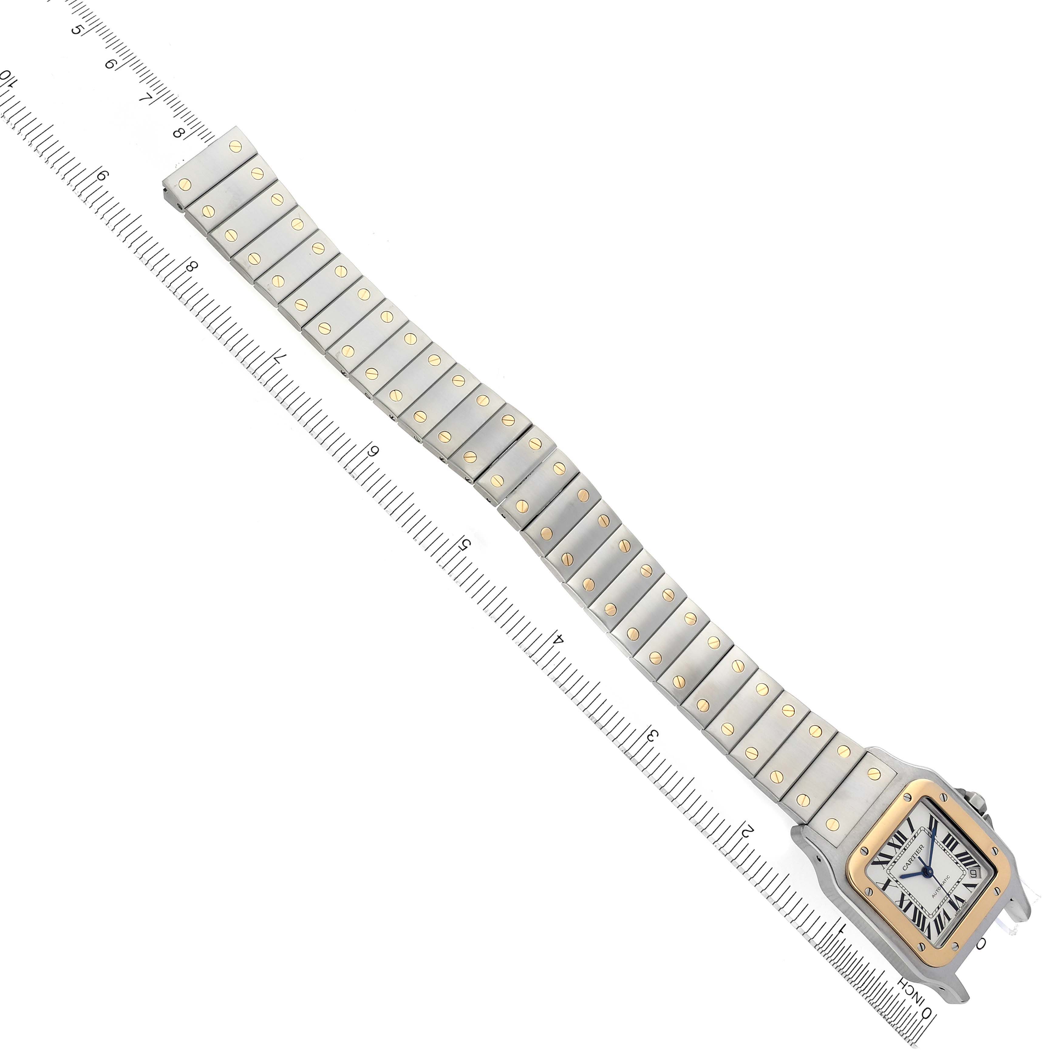 The Cartier Santos W20099C4 Men's Steel and Gold (two tone) Silver Dial W20099C4 Men's Steel and Gold (two tone) Silver Dial watch is shown in a top-down angle, displaying the entire bracelet and face alongside a ruler for scale.