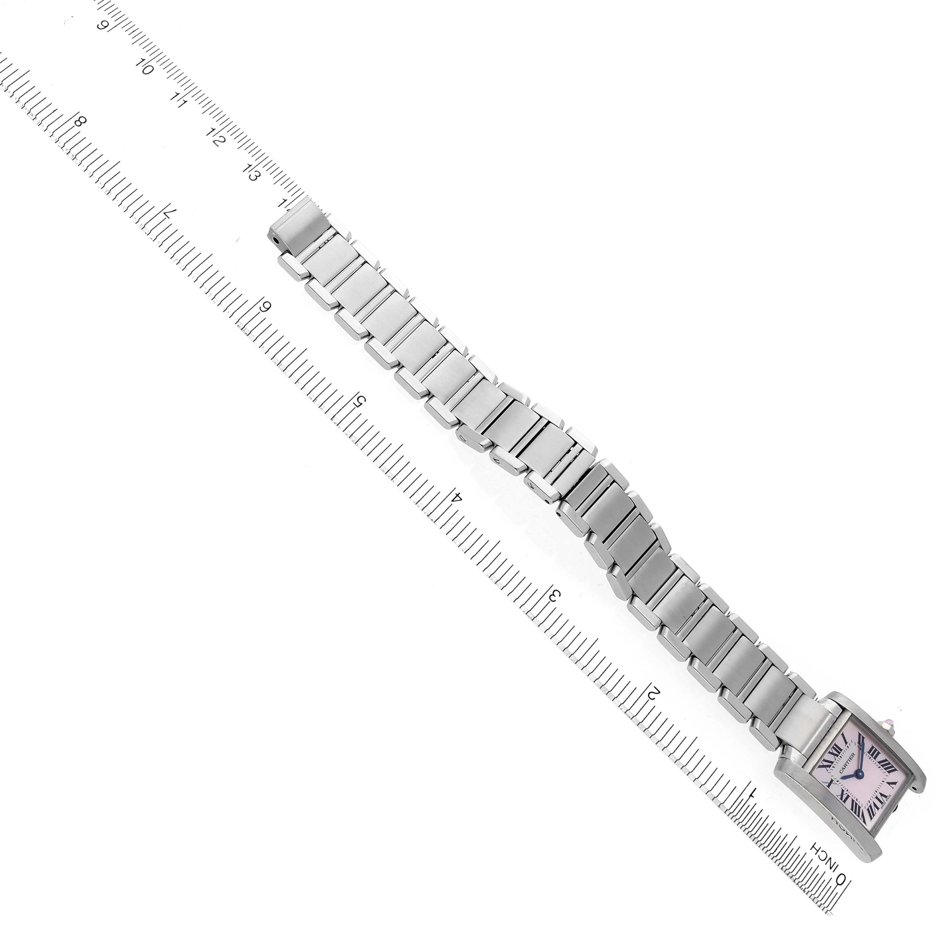 The Cartier Tank Française watch is shown from an overhead angle, displaying the full metal bracelet and rectangular face next to a ruler.
