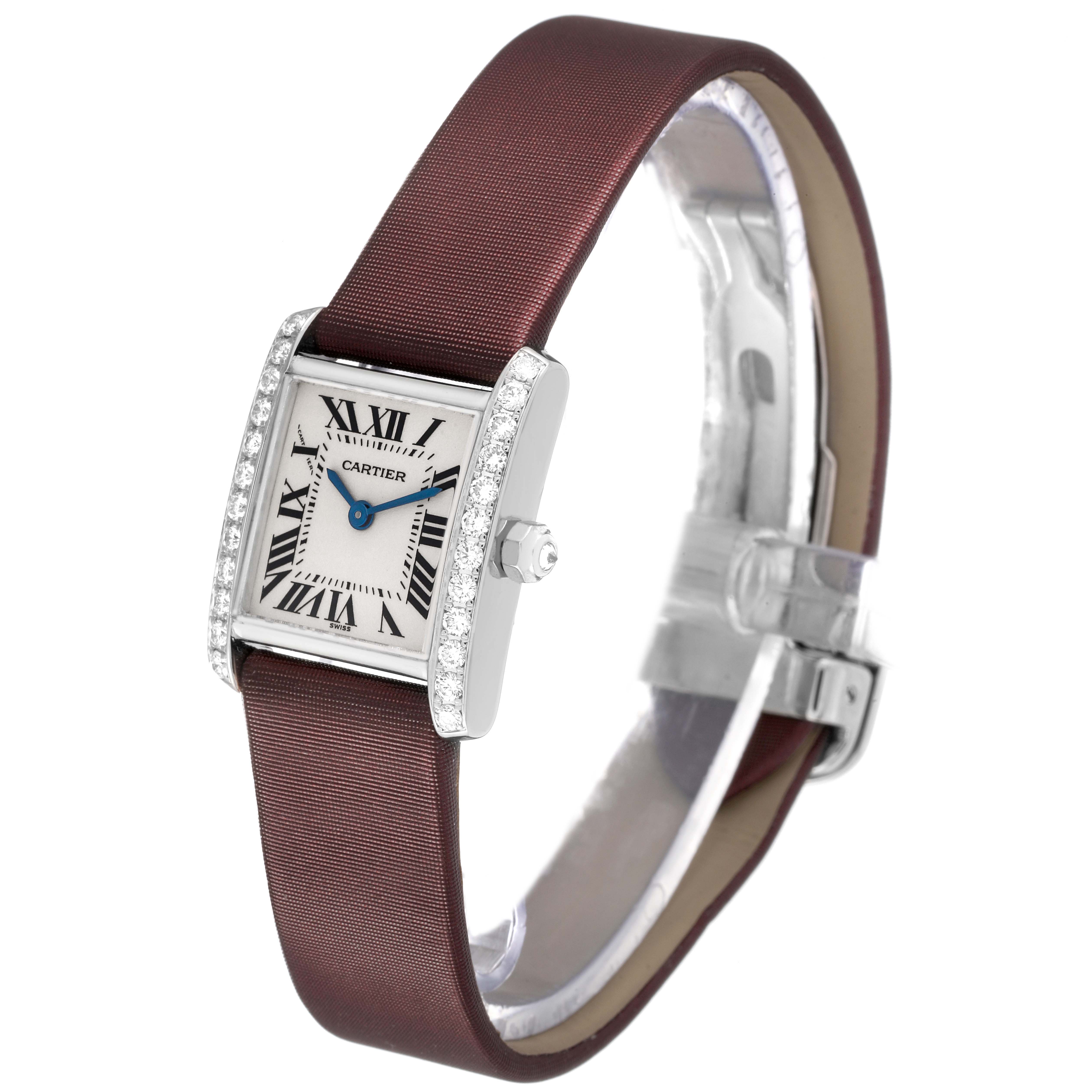 The Cartier Tank Française watch is shown from a side angle, featuring its diamond-studded bezel, blue hands, and maroon strap.