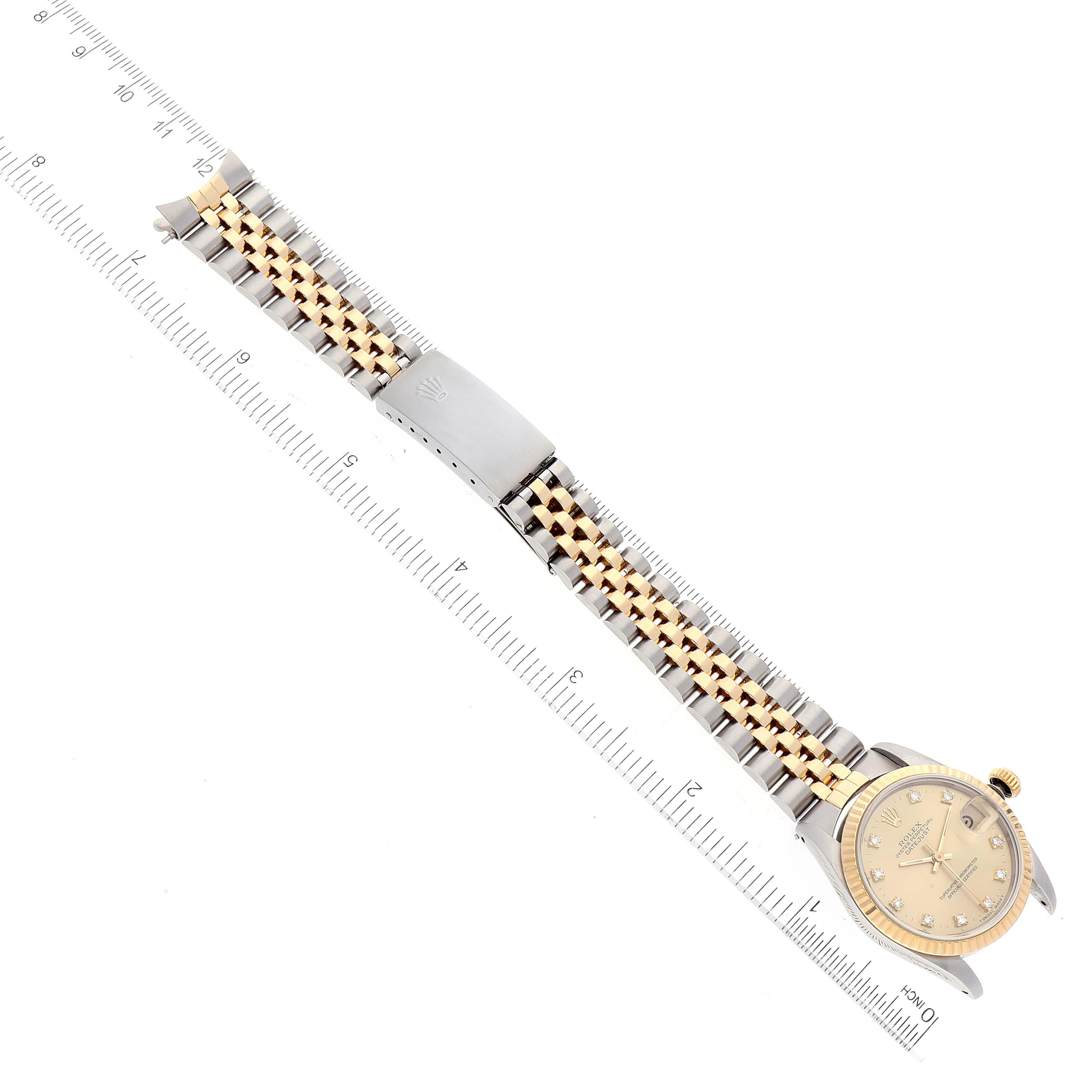 The image shows an overhead view of a Rolex Mid-Size 68273 Women
s Steel and Gold (two tone) Champagne Dial 68273 Women
s Steel and Gold (two tone) Champagne Dial watch, including the dial, bezel, and bracelet, placed next to a ruler for scale.
