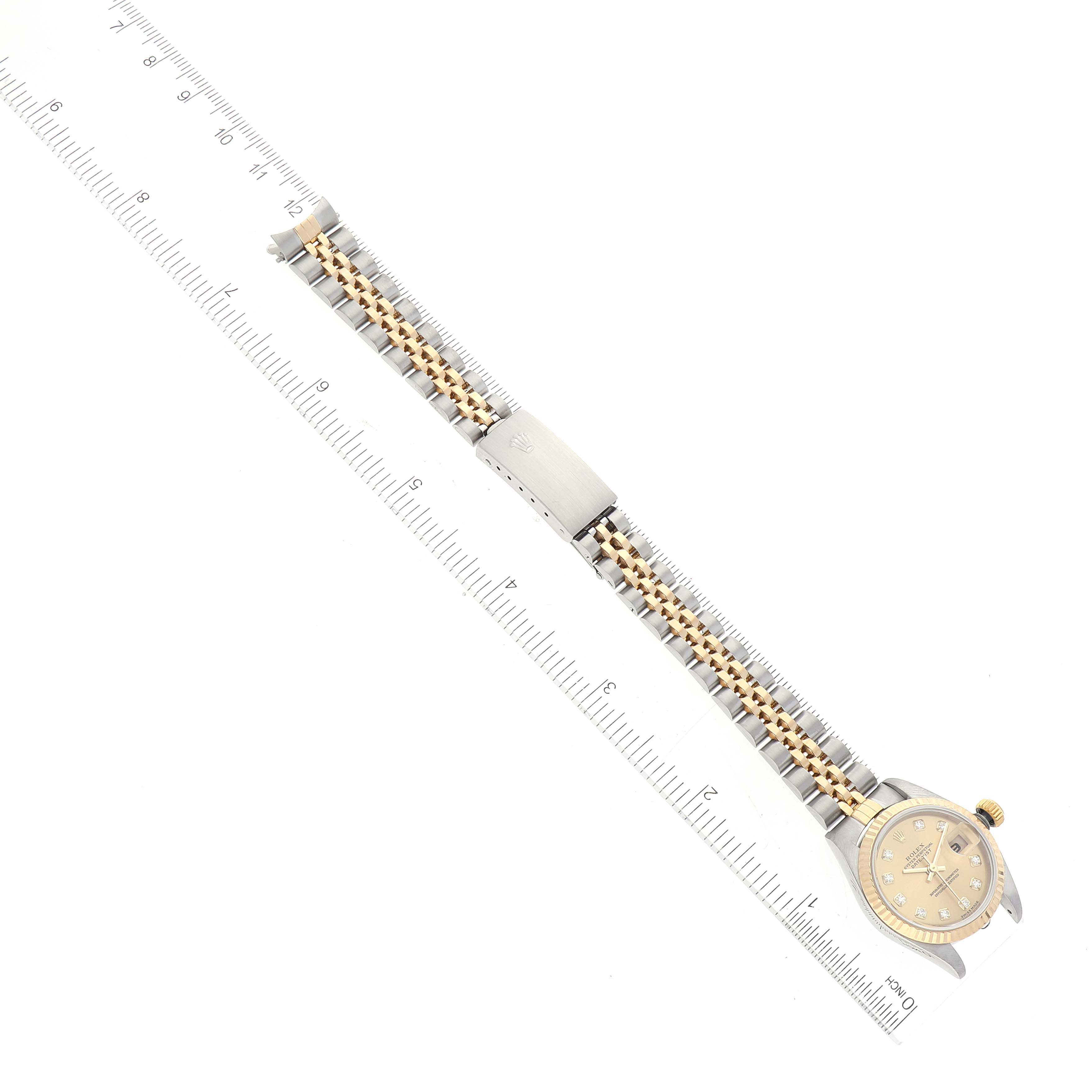 The Rolex Datejust 79173 Women's Steel and Gold (two tone) Champagne Dial 79173 Women's Steel and Gold (two tone) Champagne Dial watch is shown laid flat, highlighting the face, dial, bracelet, and clasp, measured against a ruler.