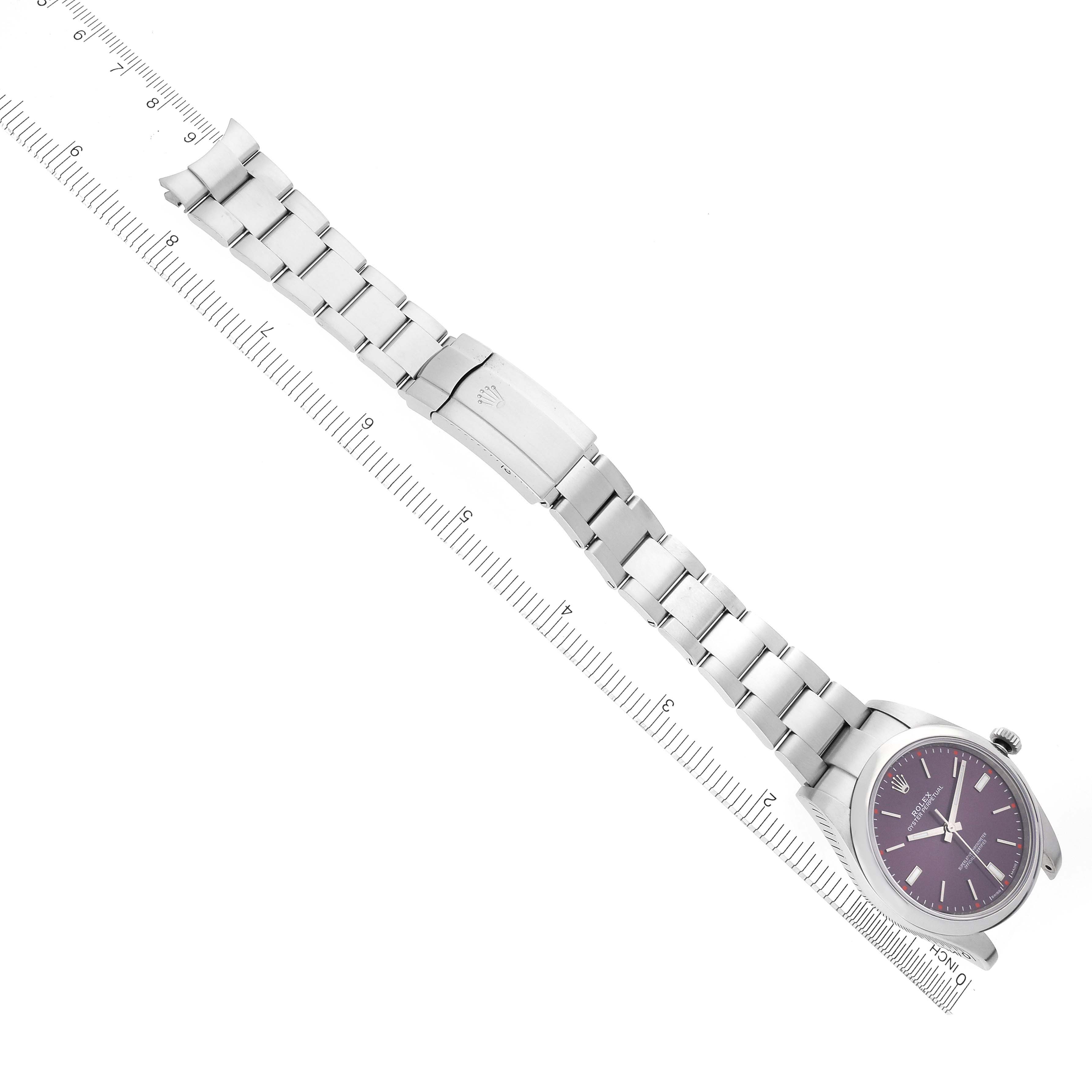 The Rolex Oyster Perpetual 114300 Men's Stainless Steel Red Dial 114300 Men's Stainless Steel Red Dial watch is shown from an overhead angle, displaying the full bracelet and a purple dial.