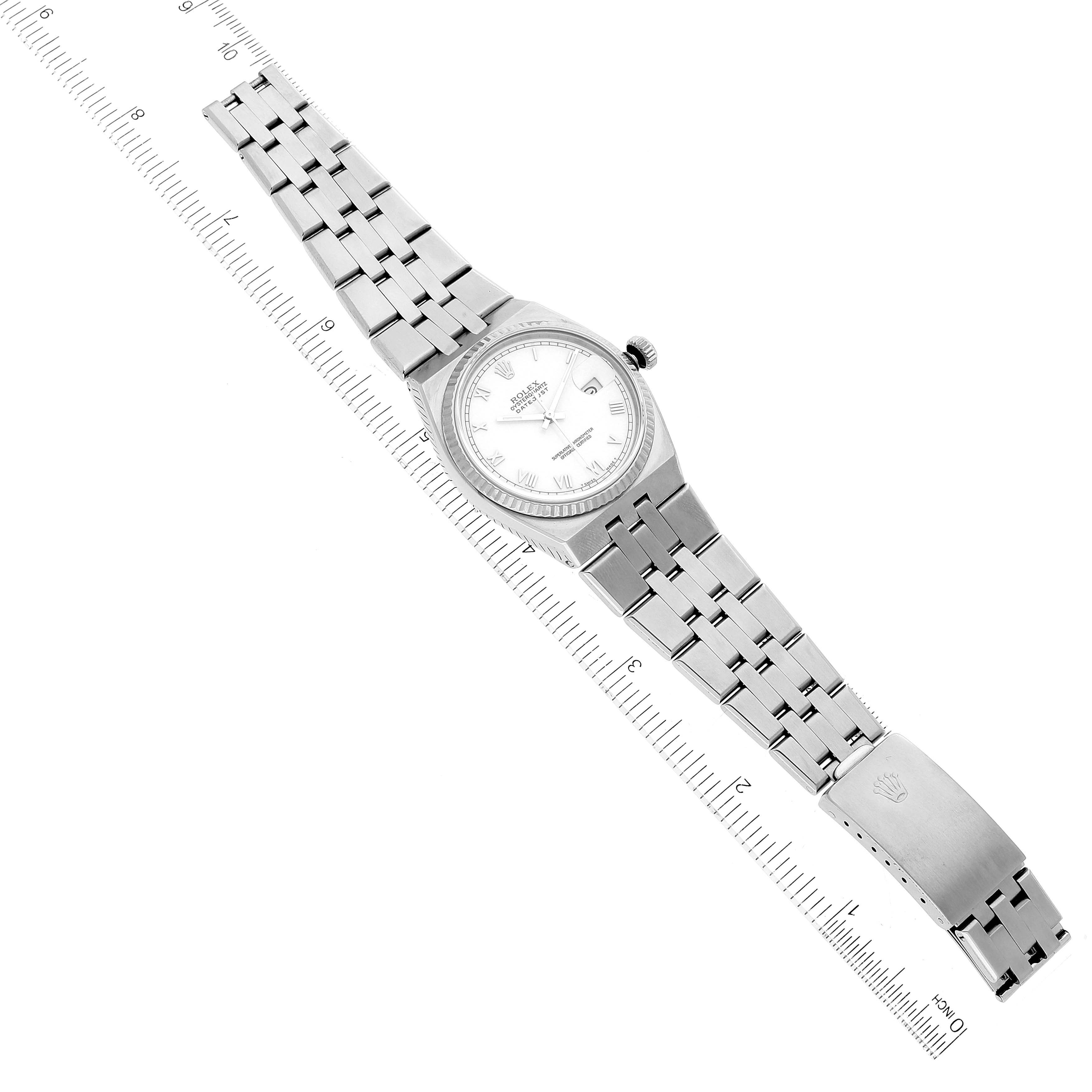 The image shows a Rolex Oysterquartz 17014 Men
s Stainless Steel White Dial 17014 Men
s Stainless Steel White Dial watch laid flat with the dial, bracelet, and clasp visible, alongside a ruler for scale.