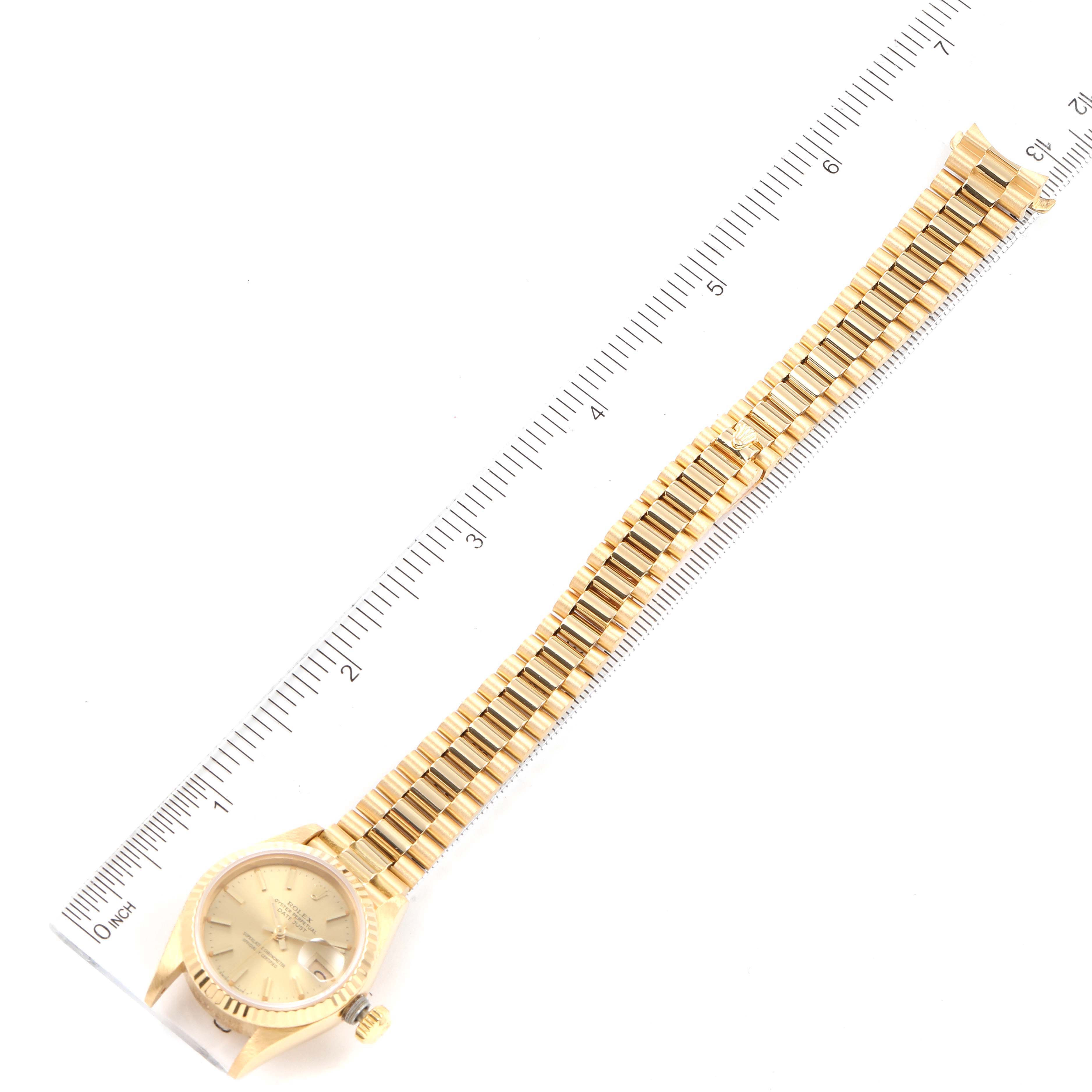 The image shows a full view of the Rolex President 69178 Women's Yellow Gold Champagne Dial 69178 Women's Yellow Gold Champagne Dial model watch, including its face, crown, and the entire bracelet with a ruler for scale.