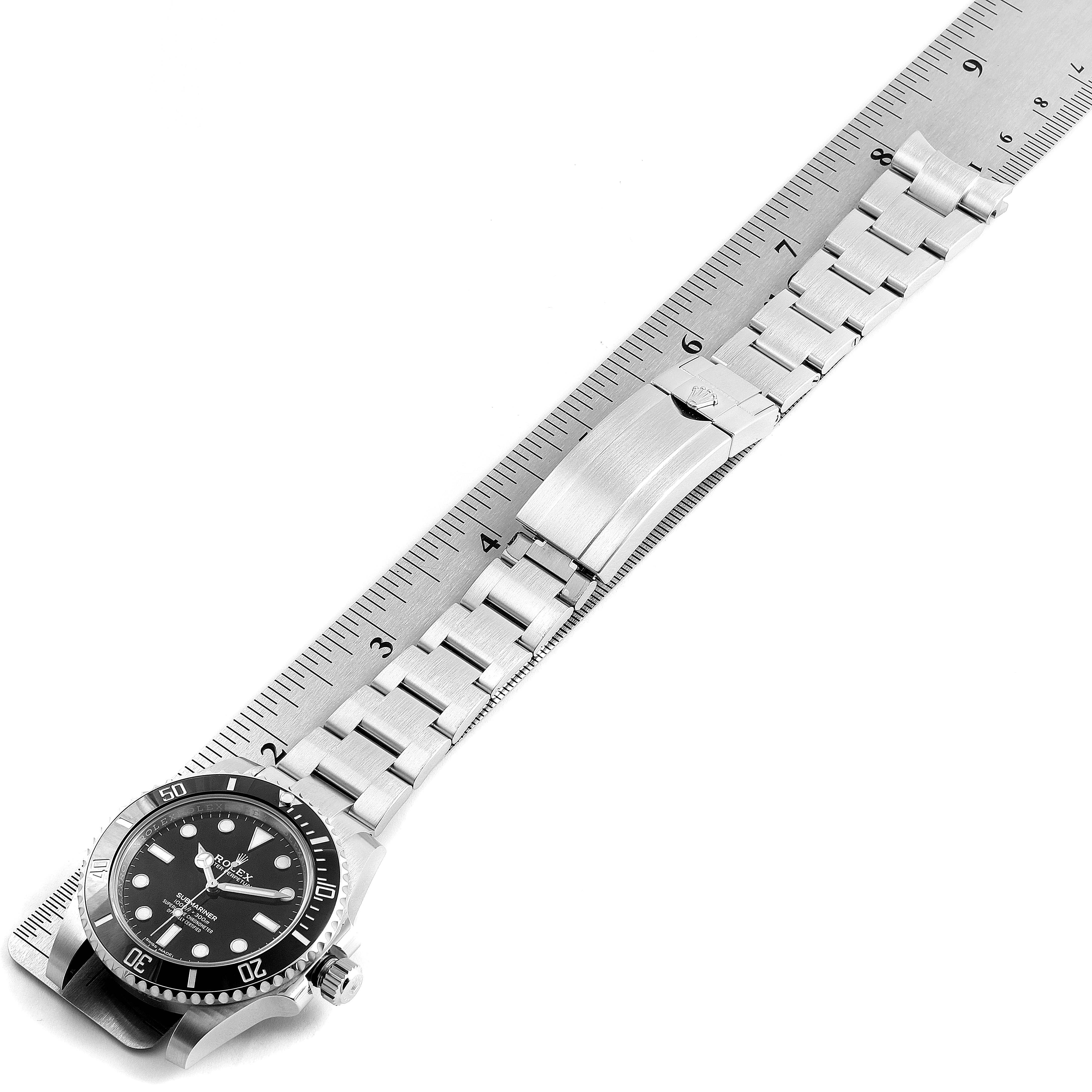 The Rolex Submariner 114060 Men
s Stainless Steel Black Dial 114060 Men
s Stainless Steel Black Dial watch is shown horizontally with its bracelet extended alongside a ruler for measurement.