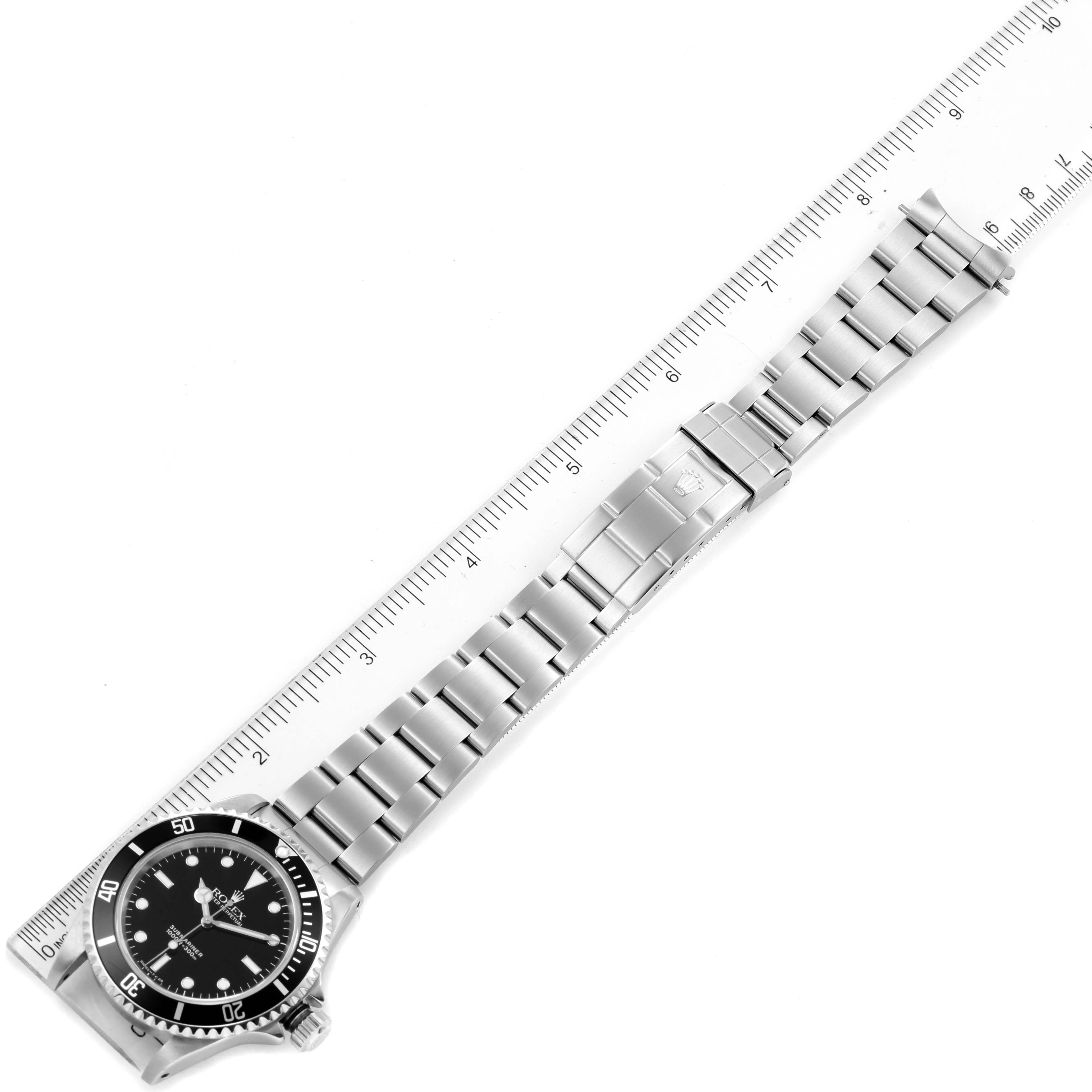This image shows a top-down view of a Rolex Submariner 14060 Men
s Stainless Steel Black Dial 14060 Men
s Stainless Steel Black Dial watch with its bracelet extended alongside a ruler.