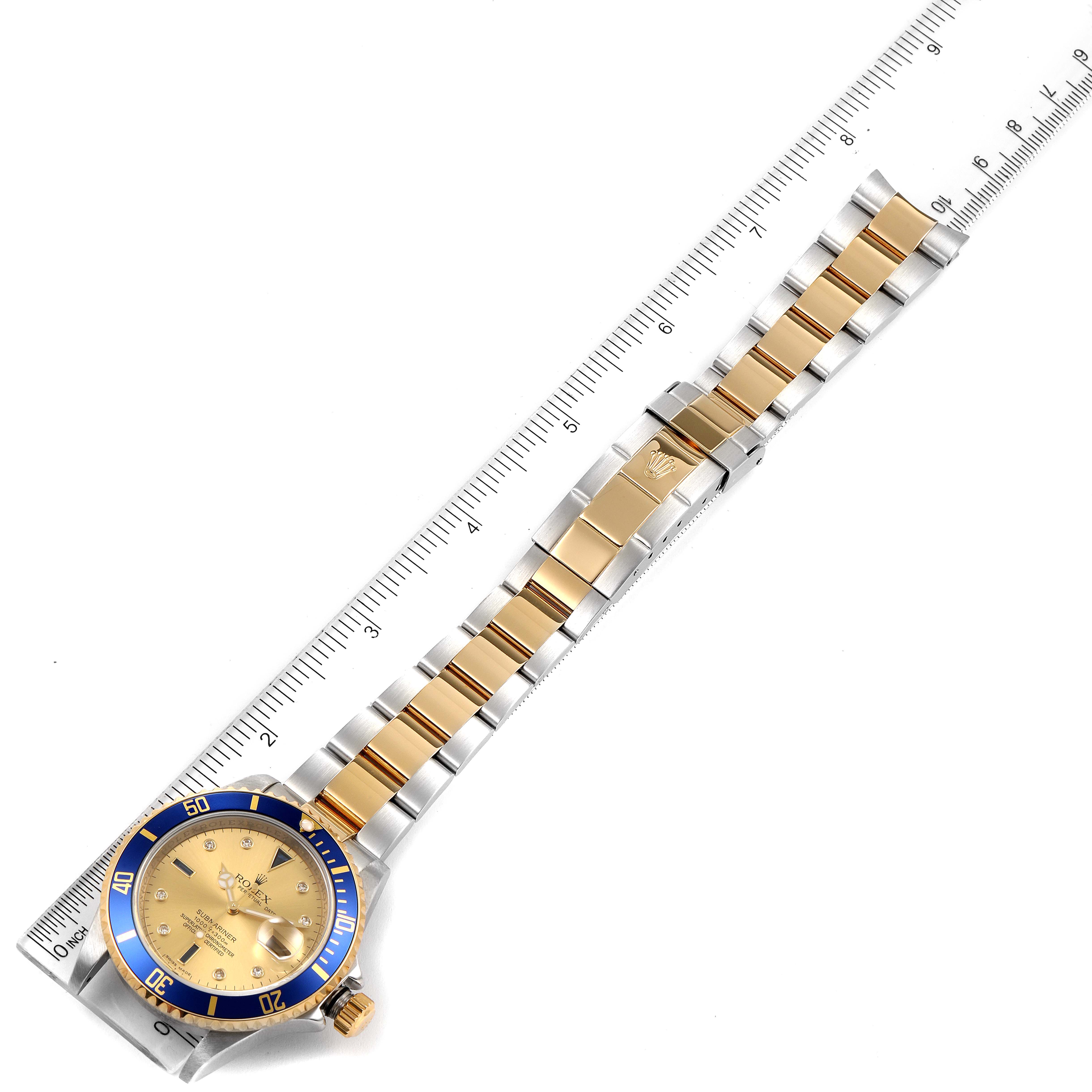 This image shows the Rolex Submariner 16613 Men
s Steel and Gold (two tone) Champagne Dial 16613 Men
s Steel and Gold (two tone) Champagne Dial watch laid flat, displaying the face, bezel, and bracelet alongside a measuring ruler.