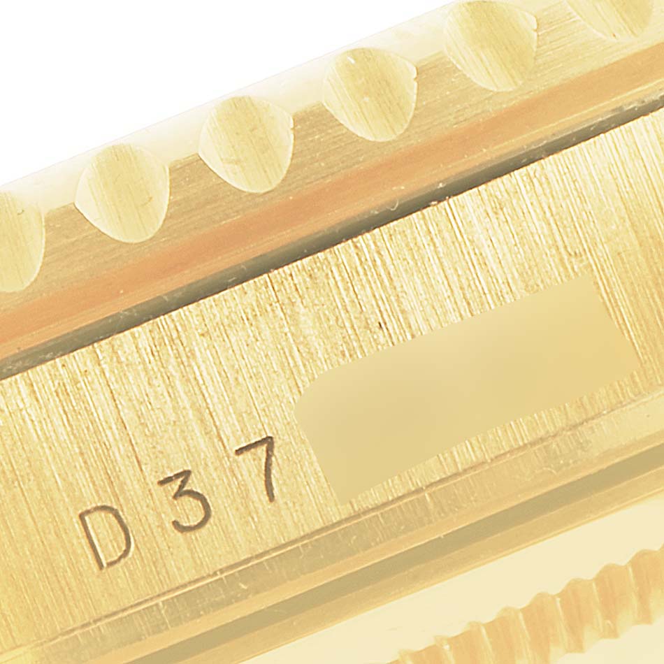 The image shows a close-up of the Rolex Submariner 16618 Men's Yellow Gold Blue Dial 16618 Men's Yellow Gold Blue Dial model's bezel and engraved serial number.