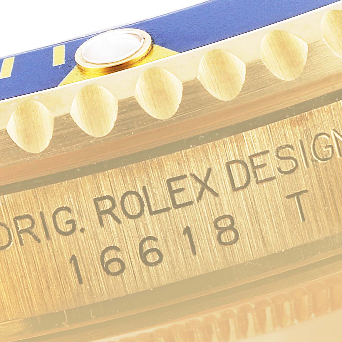 The image shows a close-up of the side of a Rolex Submariner 16618 Men's Yellow Gold Blue Dial 16618 Men's Yellow Gold Blue Dial model 16618's case, focusing on its bezel's edge and engraved design details.