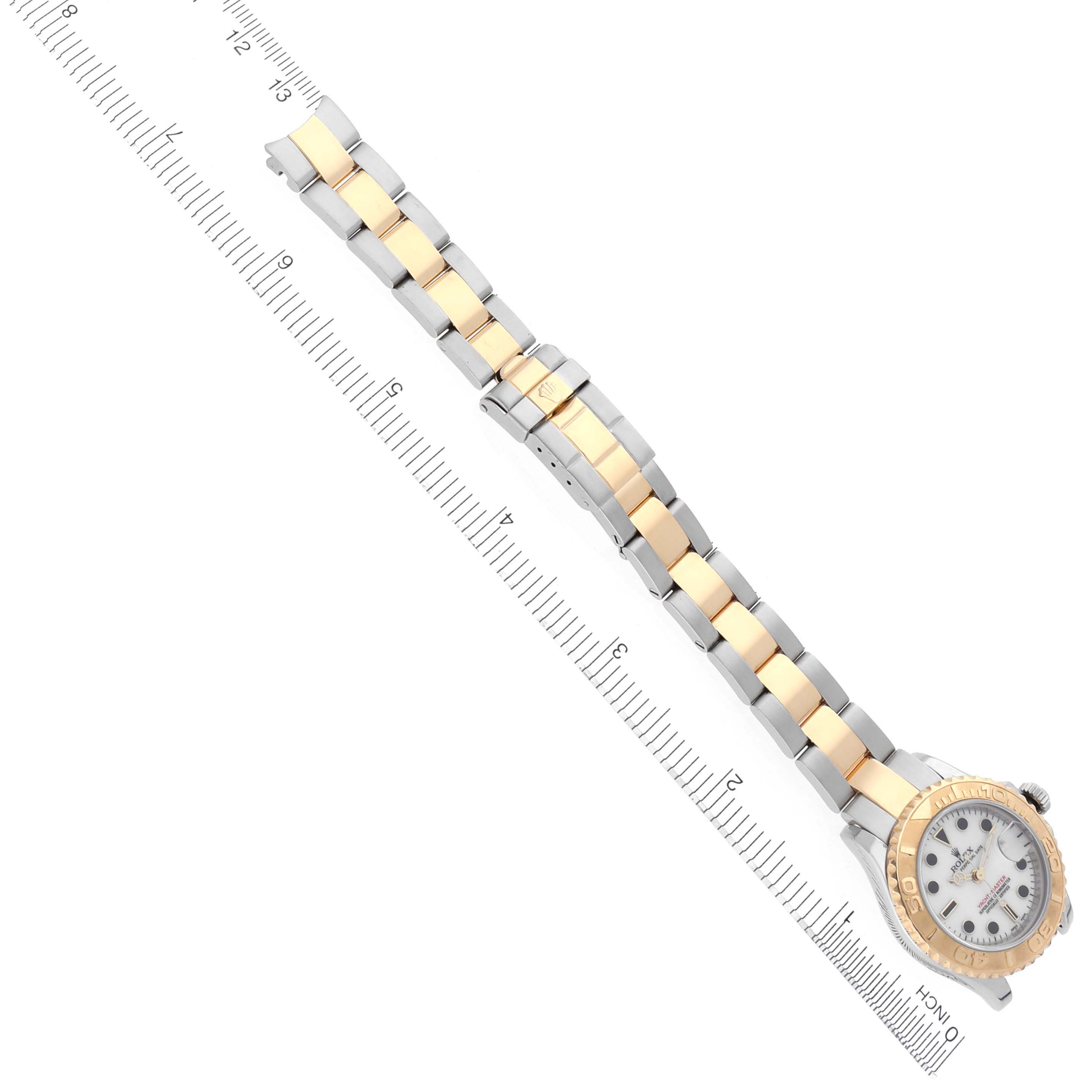 The Rolex Yacht-Master 169623 Women
s Steel and Gold (two tone) White Dial 169623 Women
s Steel and Gold (two tone) White Dial watch is shown from an overhead angle, displaying its full bracelet and face beside a ruler.