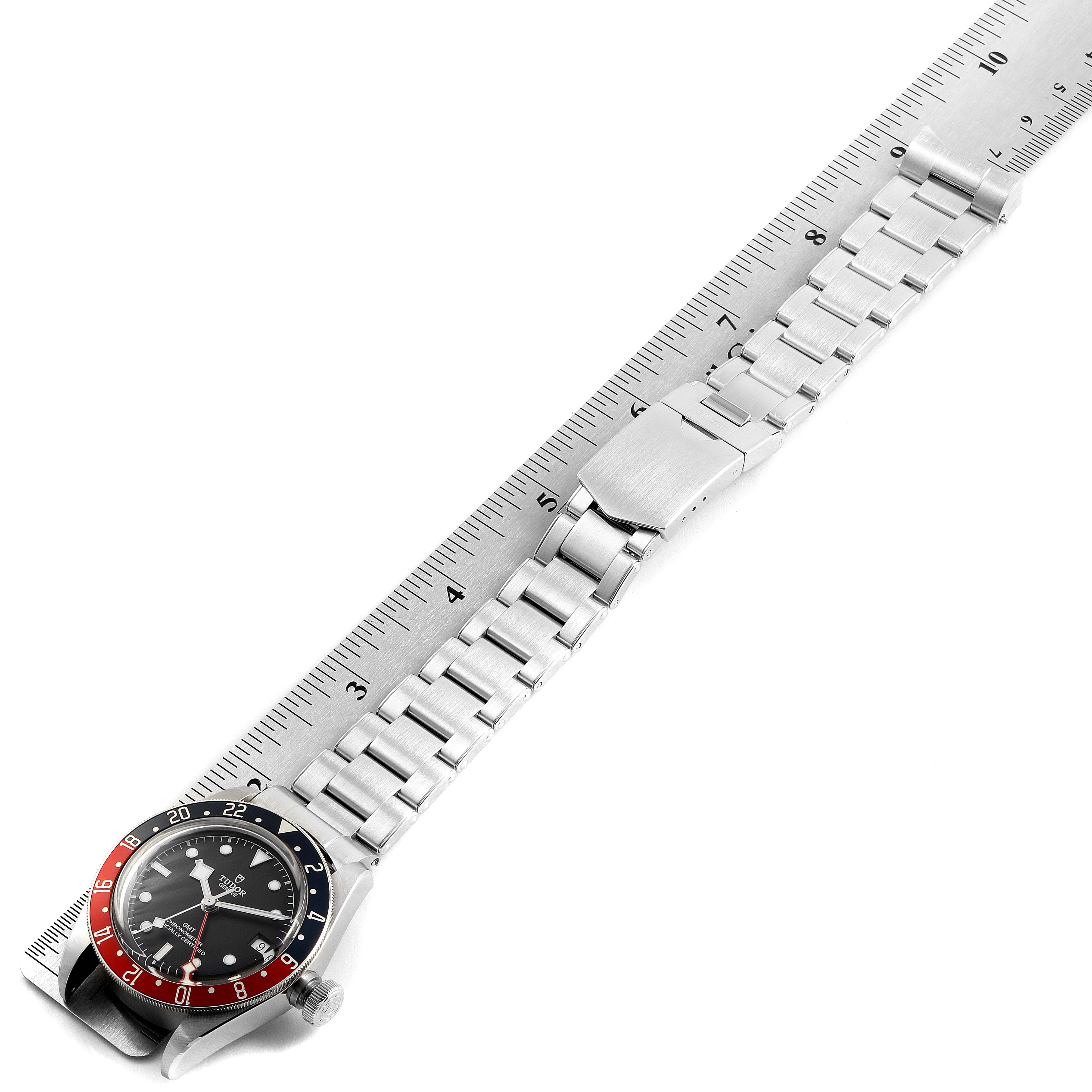 The image shows a Tudor Heritage Black Bay 79830RB Men
s Stainless Steel Black Dial 79830RB Men
s Stainless Steel Black Dial watch, positioned flat alongside a ruler, highlighting the full length of the bracelet and clasp.