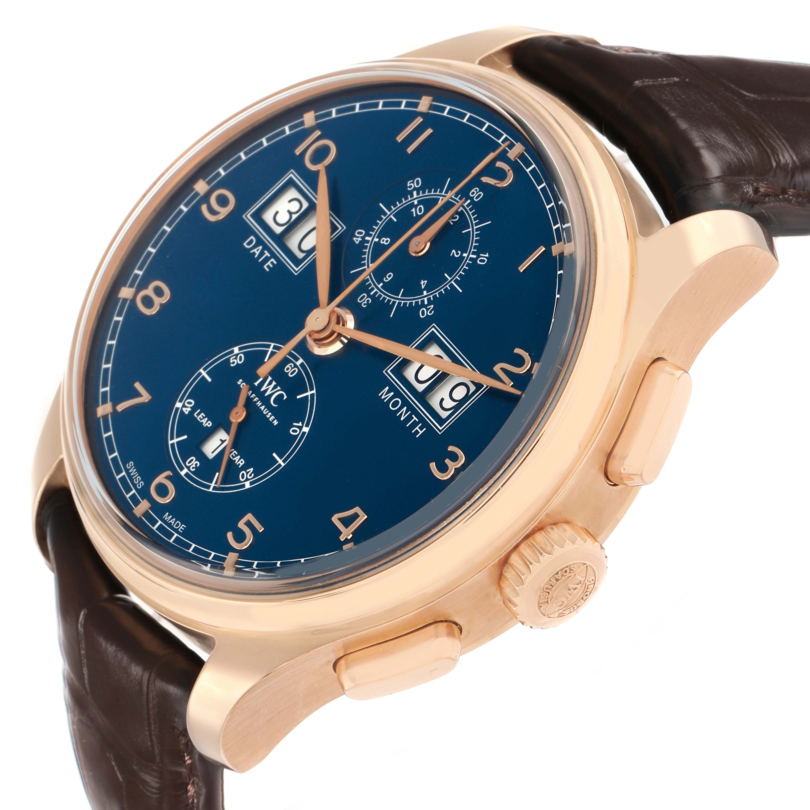 The IWC Portuguese IW397204 Men
s Rose Gold Blue Dial watch is shown from a 3/4 angle, highlighting the blue dial, gold case, crown, chronograph subdials, and leather strap.