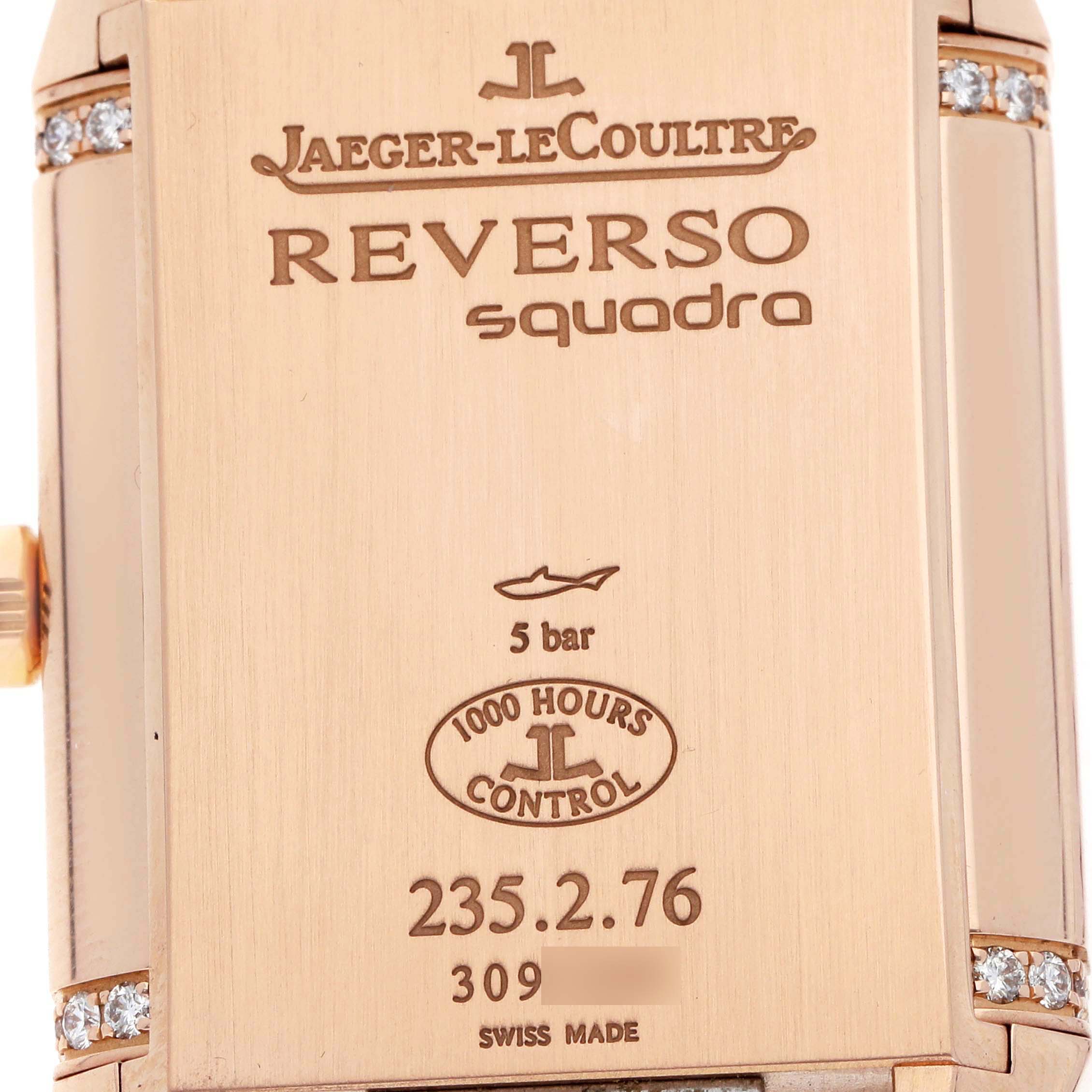 The image shows the back of a Jaeger-LeCoultre Reverso watch, featuring engravings and decorative elements.