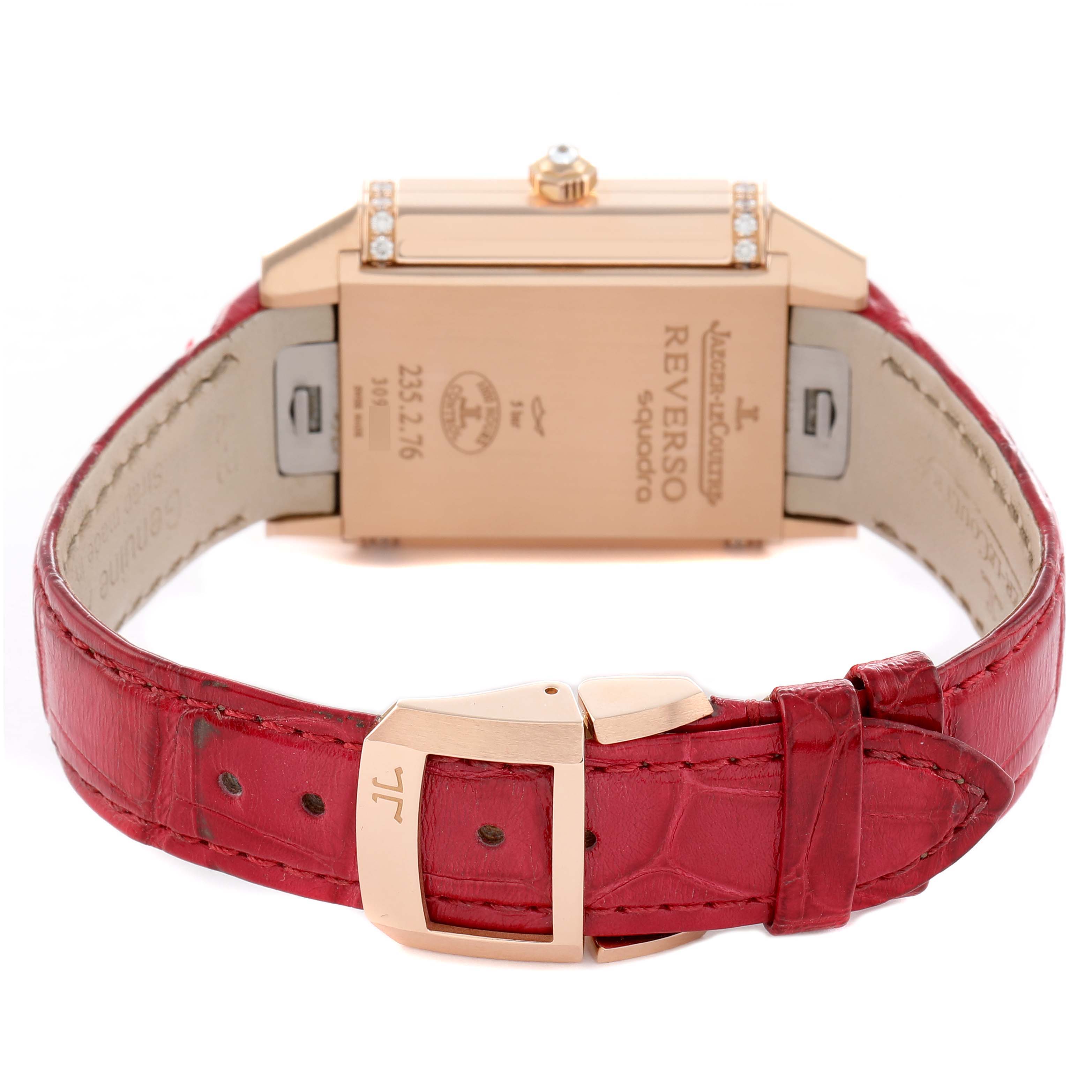 The Jaeger-LeCoultre Reverso watch is shown from the rear, displaying the case back and red leather strap with buckle.
