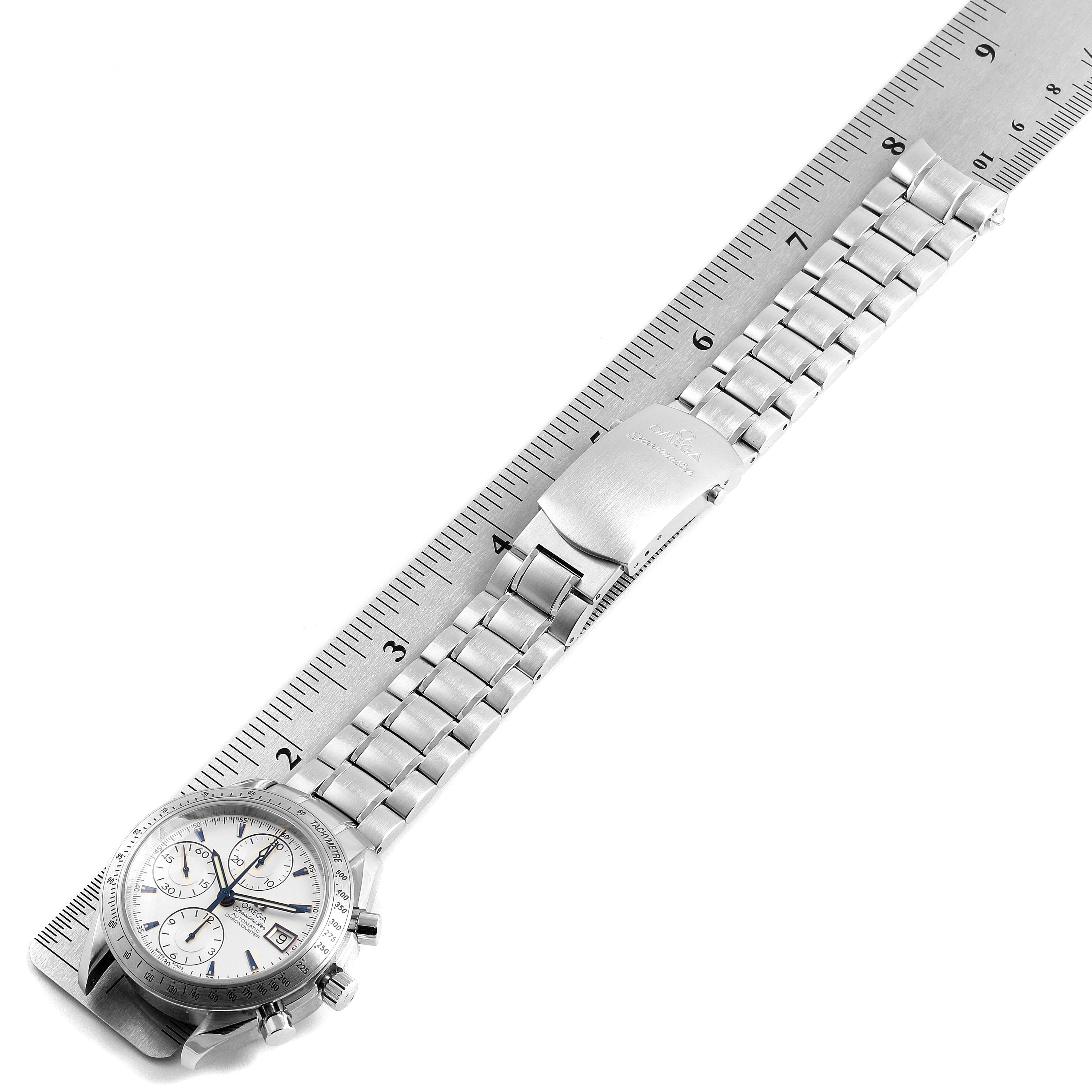 The image shows an Omega Speedmaster 3211.32.00 Men
s Stainless Steel Silver Dial 3211.32.00 Men
s Stainless Steel Silver Dial watch at an angle with its face and stainless steel bracelet laid adjacent to a ruler.