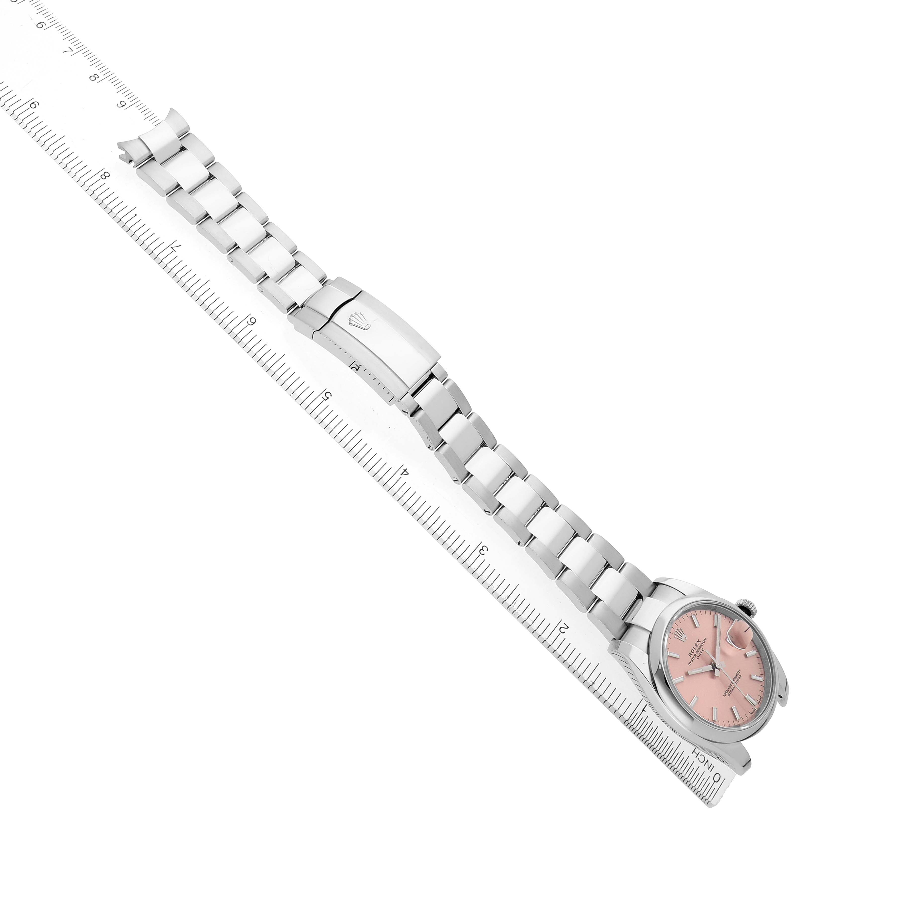 The Rolex Oyster Perpetual 115200 Men
s Stainless Steel Pink Dial watch is shown at a diagonal angle, displaying the face, bezel, and full bracelet alongside a ruler.