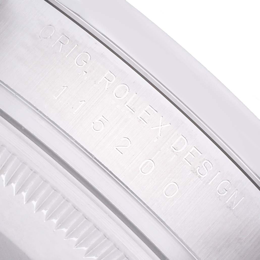 The image shows an angled close-up of the inner bezel of a Rolex Oyster Perpetual 115200 Men
s Stainless Steel Pink Dial, displaying the engraved model details.