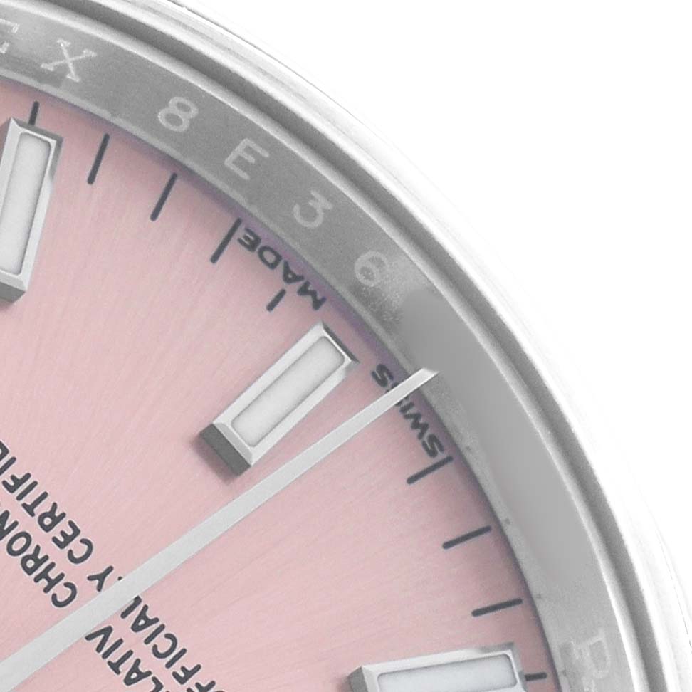 The image shows a close-up of the dial and bezel of a Rolex Oyster Perpetual 115200 Men
s Stainless Steel Pink Dial, highlighting the indices and part of the watch
s text.