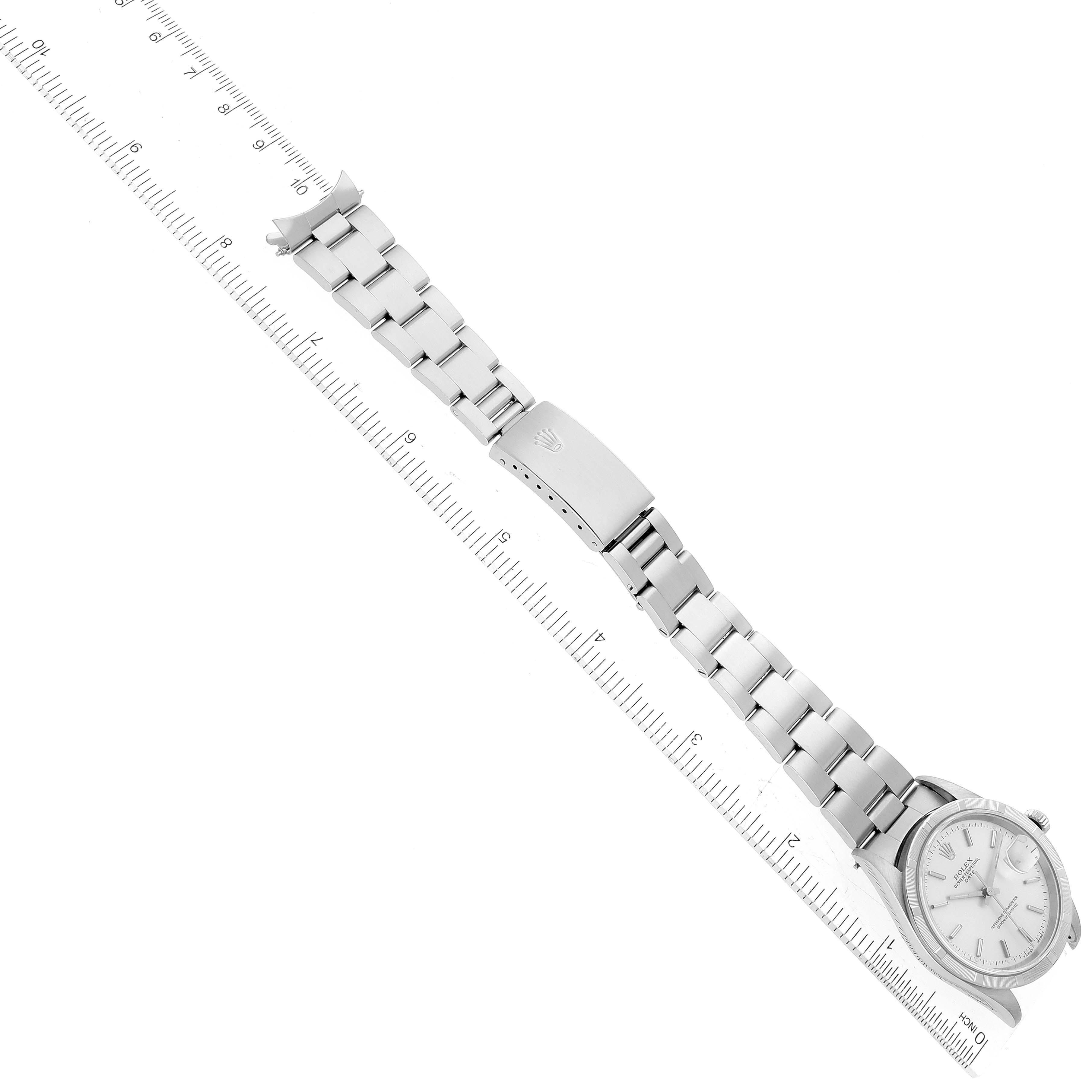 The image shows a Rolex Date 15210 Men
s Stainless Steel Silver Dial 15210 Men
s Stainless Steel Silver Dial model watch angled diagonally, displaying the watch face, bracelet, and clasp alongside a ruler.