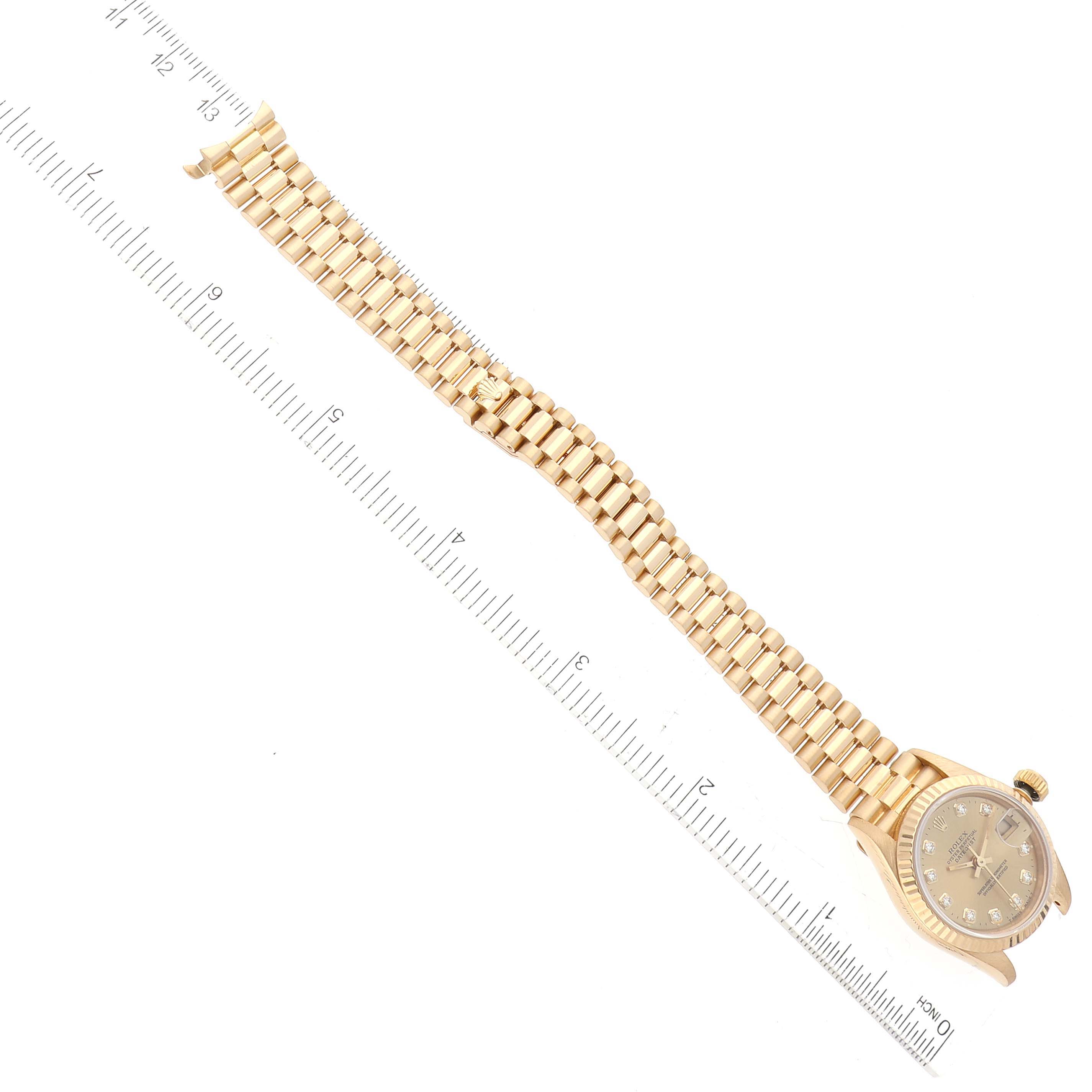 The Rolex President 69178 Women's Yellow Gold Champagne Dial 69178 Women's Yellow Gold Champagne Dial model watch is shown from a top-down angle displaying the entire face and bracelet next to a ruler.