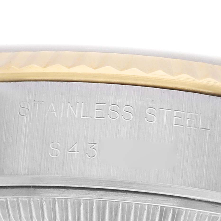 The image shows a close-up of the stainless steel casing edge of a Rolex Datejust 69173 Women
s Steel and Gold (two tone) Champagne Dial, highlighting engravings.