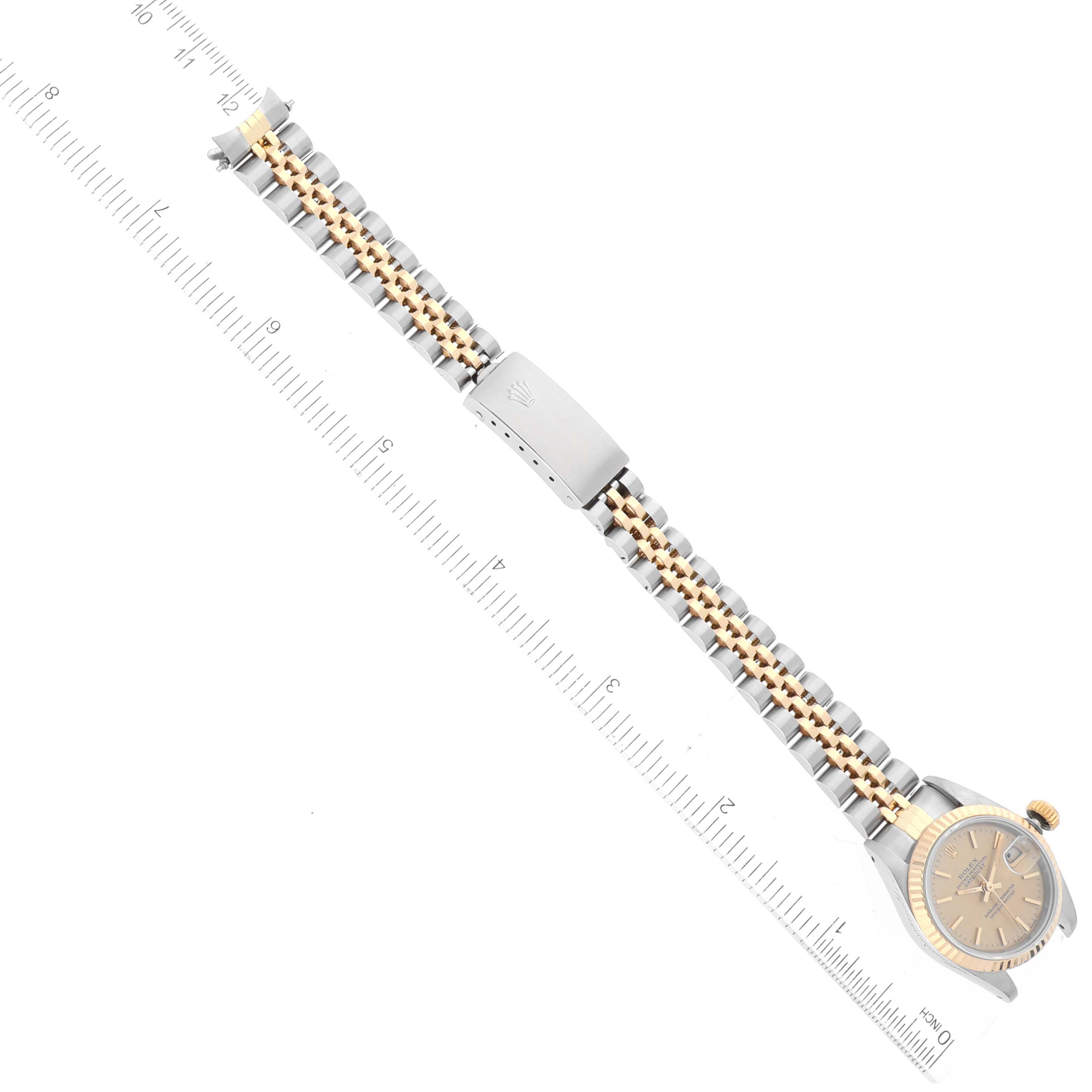The image shows a Rolex Datejust 69173 Women
s Steel and Gold (two tone) Champagne Dial 69173 Women
s Steel and Gold (two tone) Champagne Dial watch with a full view of the band, clasp, and partially the face, placed alongside a ruler for scale.