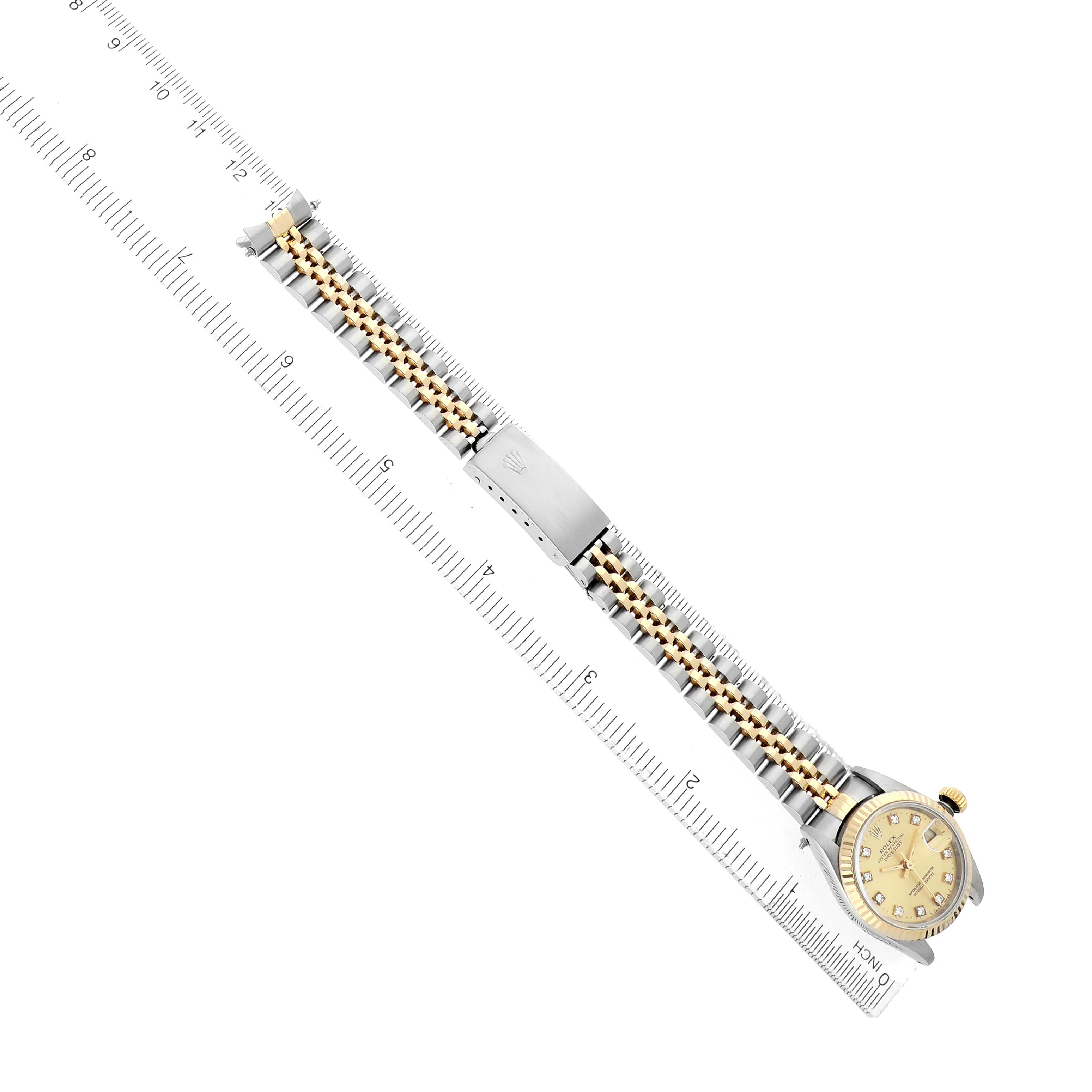 The Rolex Datejust 69173 Women
s Steel and Gold (two tone) Champagne Dial watch is shown from a top-down angle, displaying both the dial and the bracelet with a ruler for scale.