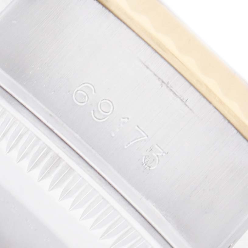 The image shows a close-up of the side of a Rolex Datejust 69173 Women
s Steel and Gold (two tone) Champagne Dial, displaying part of the bezel and engraved numbers.