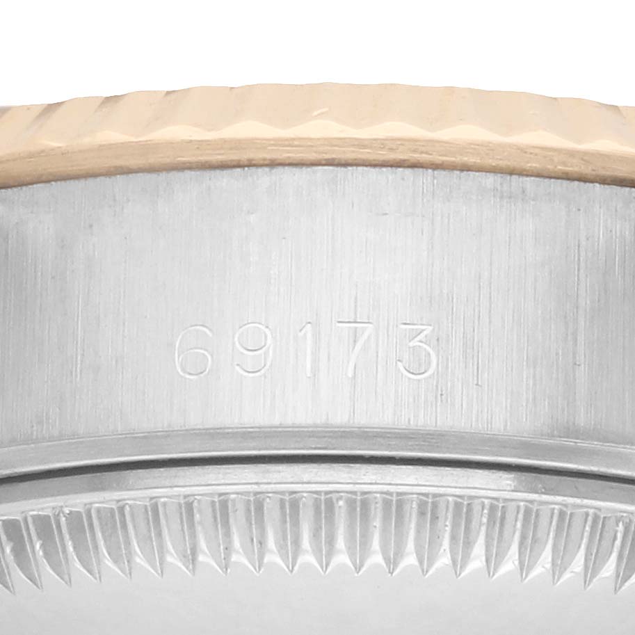 The image shows a close-up view of the side of the Rolex Datejust 69173 Women
s Steel and Gold (two tone) Black Dial, featuring part of the bezel and serial number.