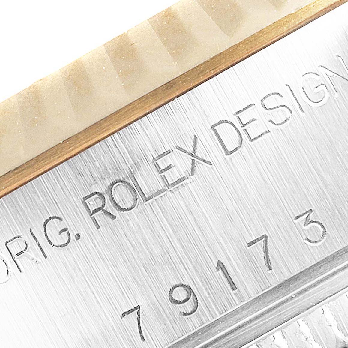 This close-up image shows the engraved "ROLEX DESIGN" and serial number on the case of a Rolex Datejust 79173 Women's Steel and Gold (two tone) Champagne Dial 79173 Women's Steel and Gold (two tone) Champagne Dial watch.