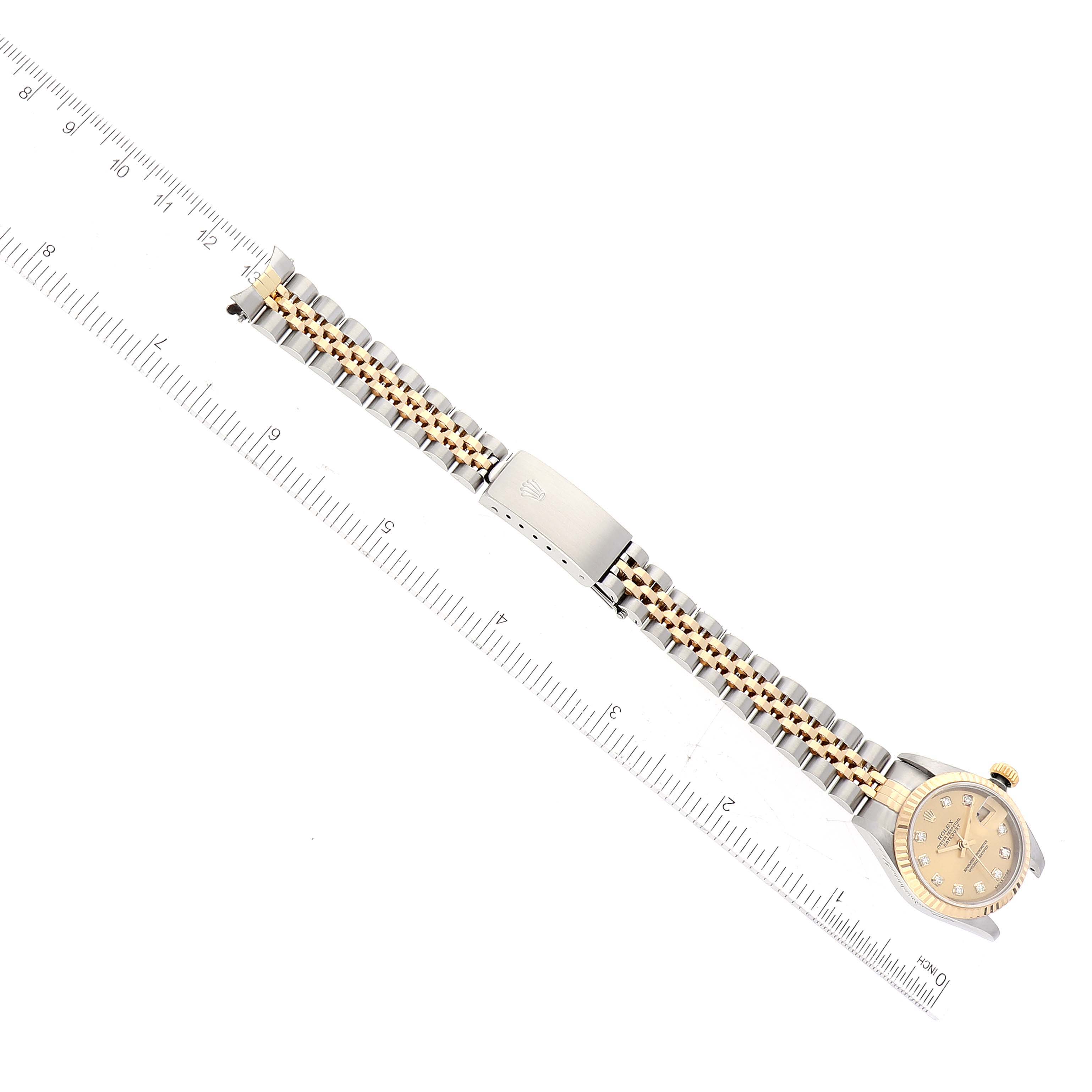 The Datejust model by Rolex is shown from a top-down angle, displaying the watch face, bracelet, and clasp alongside a ruler for scale.