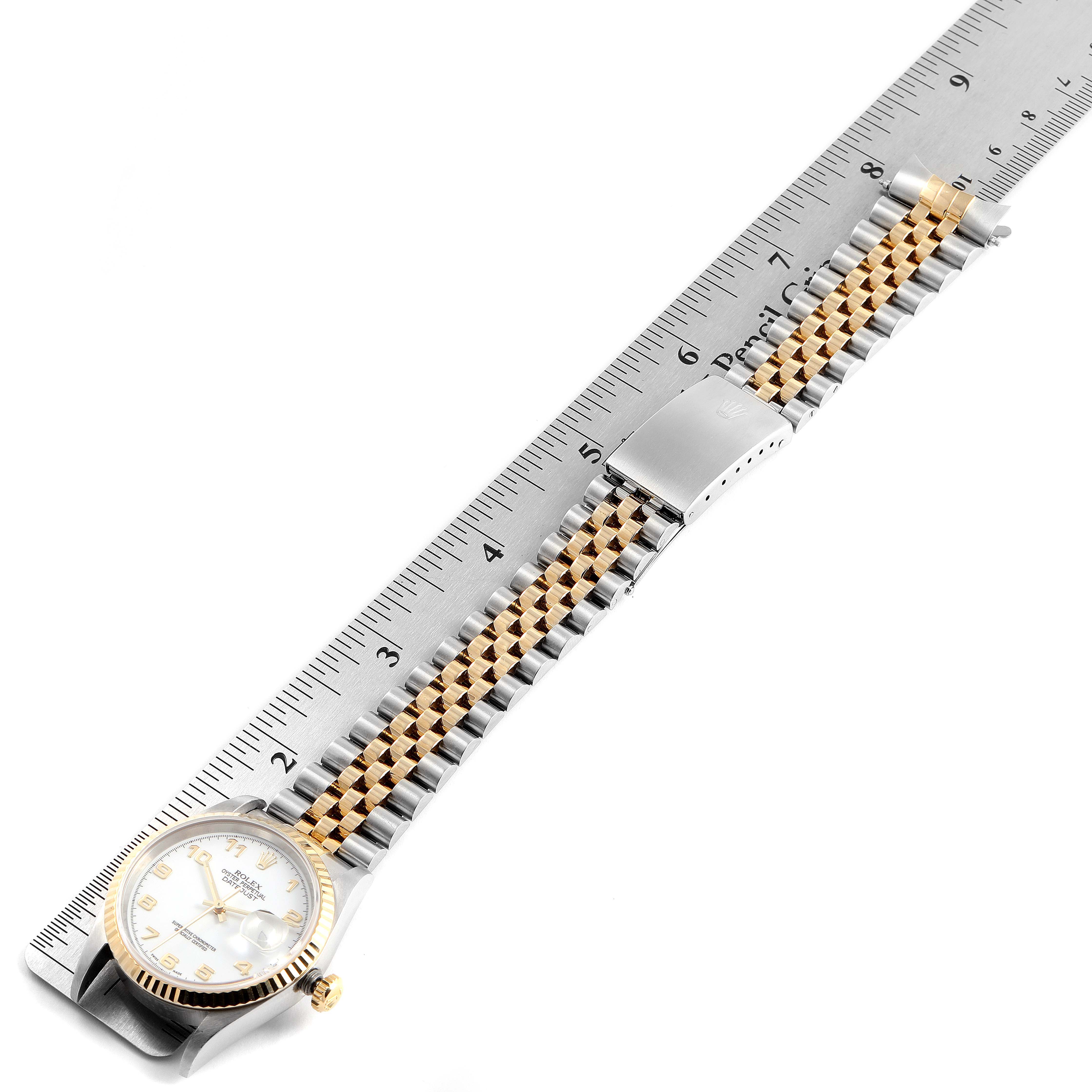 The Rolex Datejust 16233 Men's Steel and Gold (two tone) White Dial 16233 Men's Steel and Gold (two tone) White Dial watch is shown flat with the dial, crown, and stretch of the bracelet visible, alongside a ruler.
