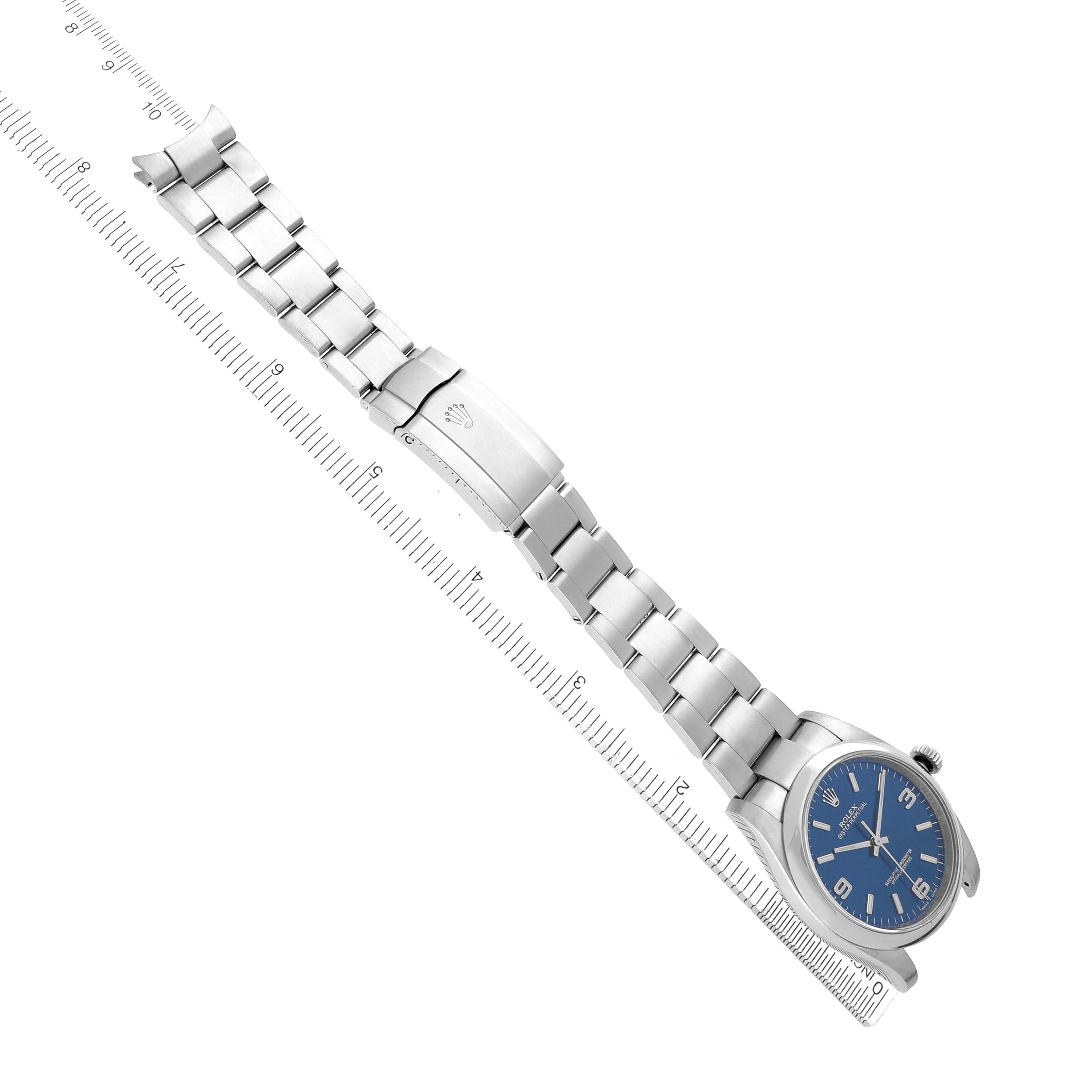 The image shows a Rolex Oyster Perpetual 116000 Men
s Stainless Steel Blue Dial watch diagonally from above, highlighting its bracelet, clasp, and blue dial.