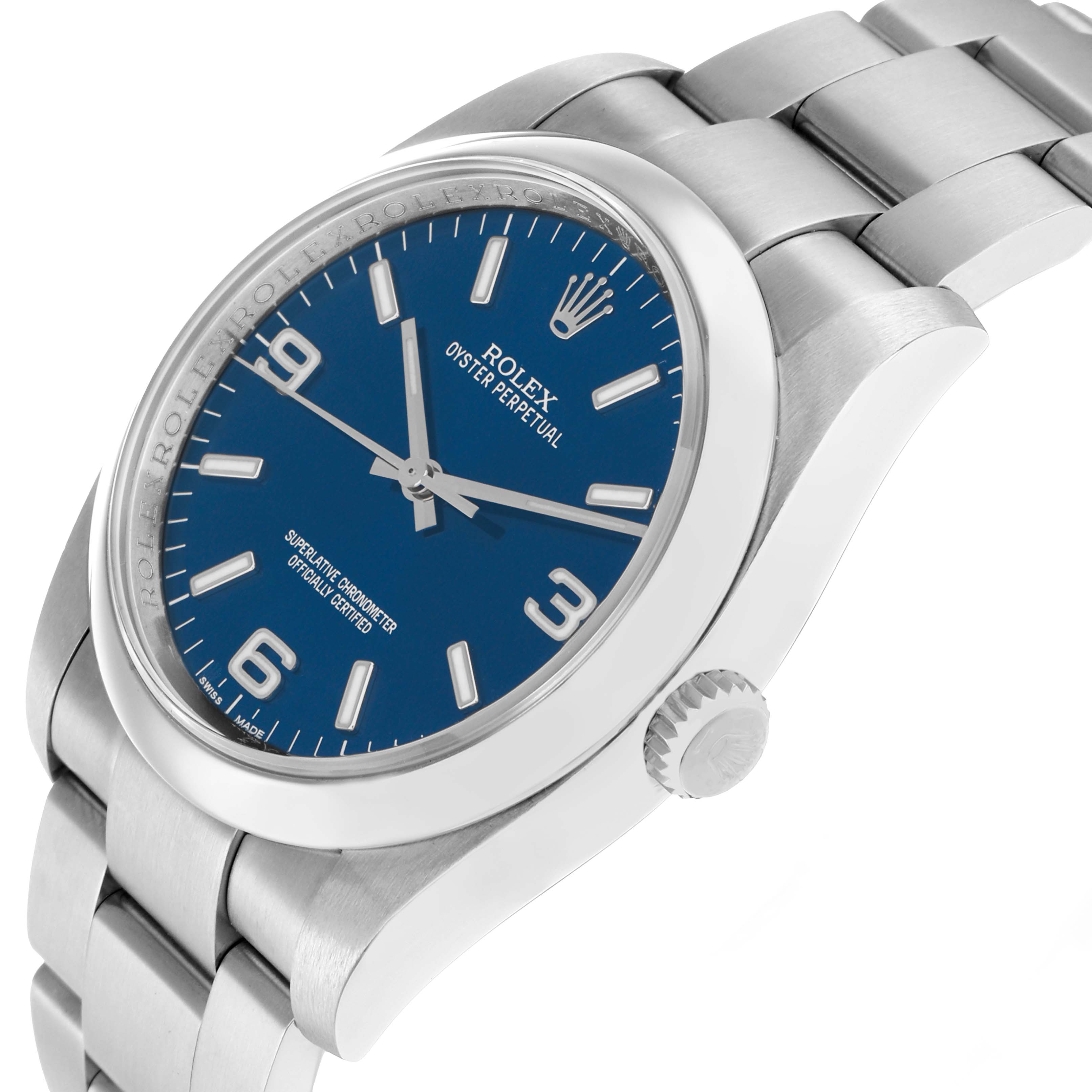 The Rolex Oyster Perpetual 116000 Men
s Stainless Steel Blue Dial watch is shown in a tilted side view, displaying the blue dial, bezel, crown, and part of the bracelet.