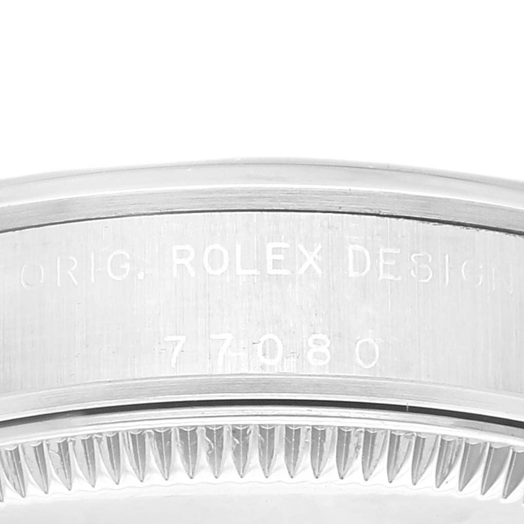 This image shows a close-up of the side of a Rolex Oyster Perpetual 77080 Women's Stainless Steel Brown Dial 77080 Women's Stainless Steel Brown Dial watch, featuring the engraved "Rolex Design" and a serial number.