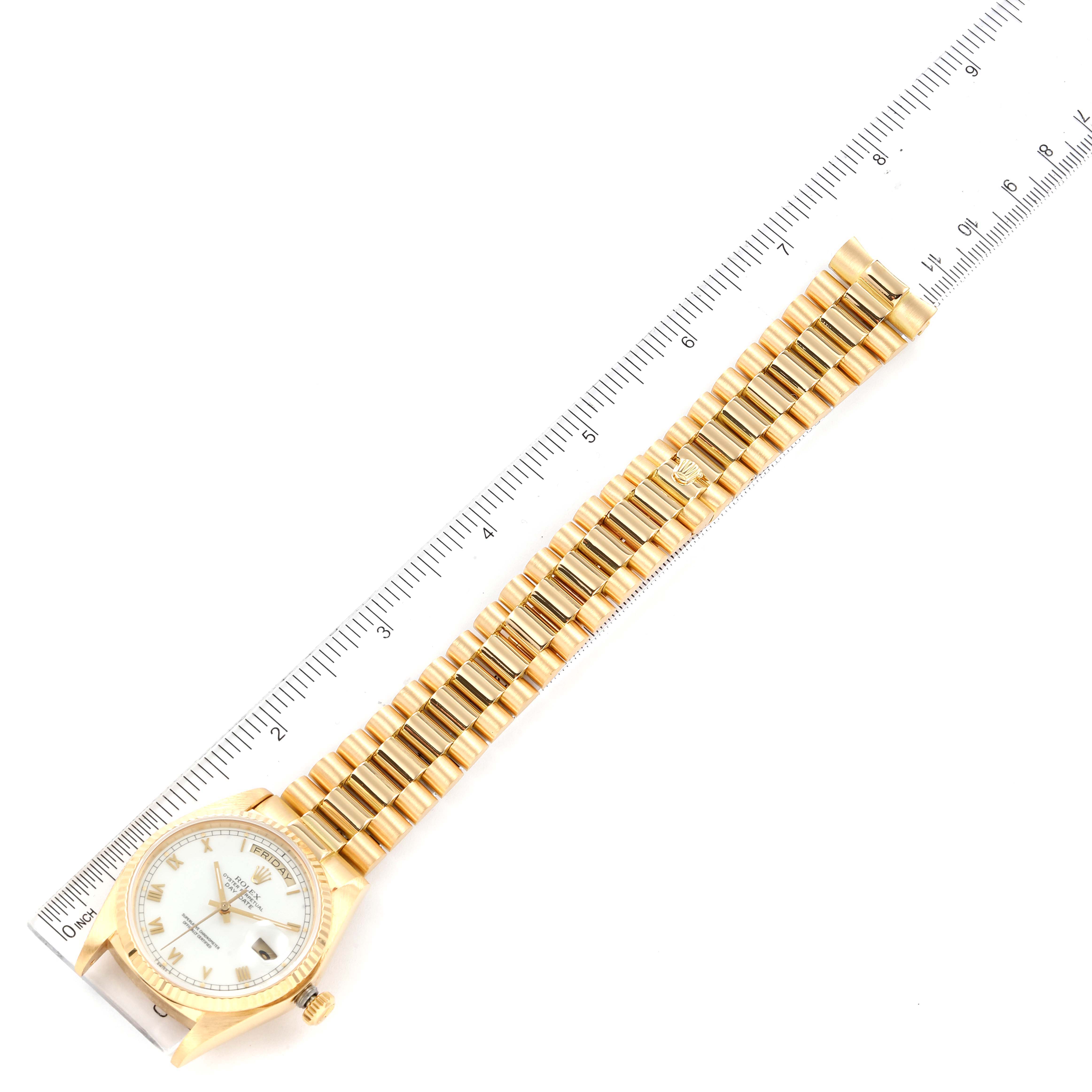 The Rolex President 18038 Men's Yellow Gold White Dial 18038 Men's Yellow Gold White Dial model watch is shown from a top-down angle, capturing the face and entire bracelet, aligned with a ruler.