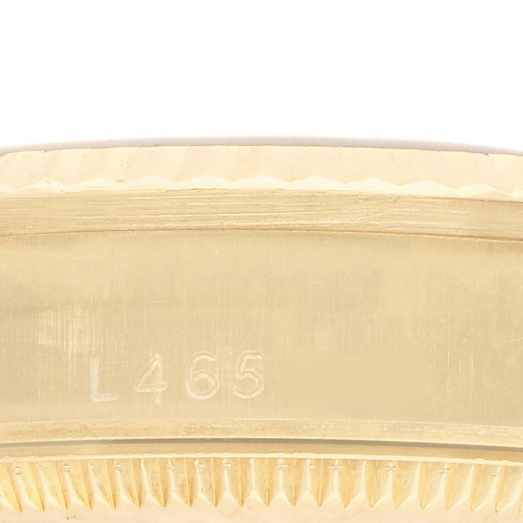 The image shows a close-up of the side of a Rolex President 68278 Women
s Yellow Gold Black Dial model, focusing on its case edge with an engraved serial number.