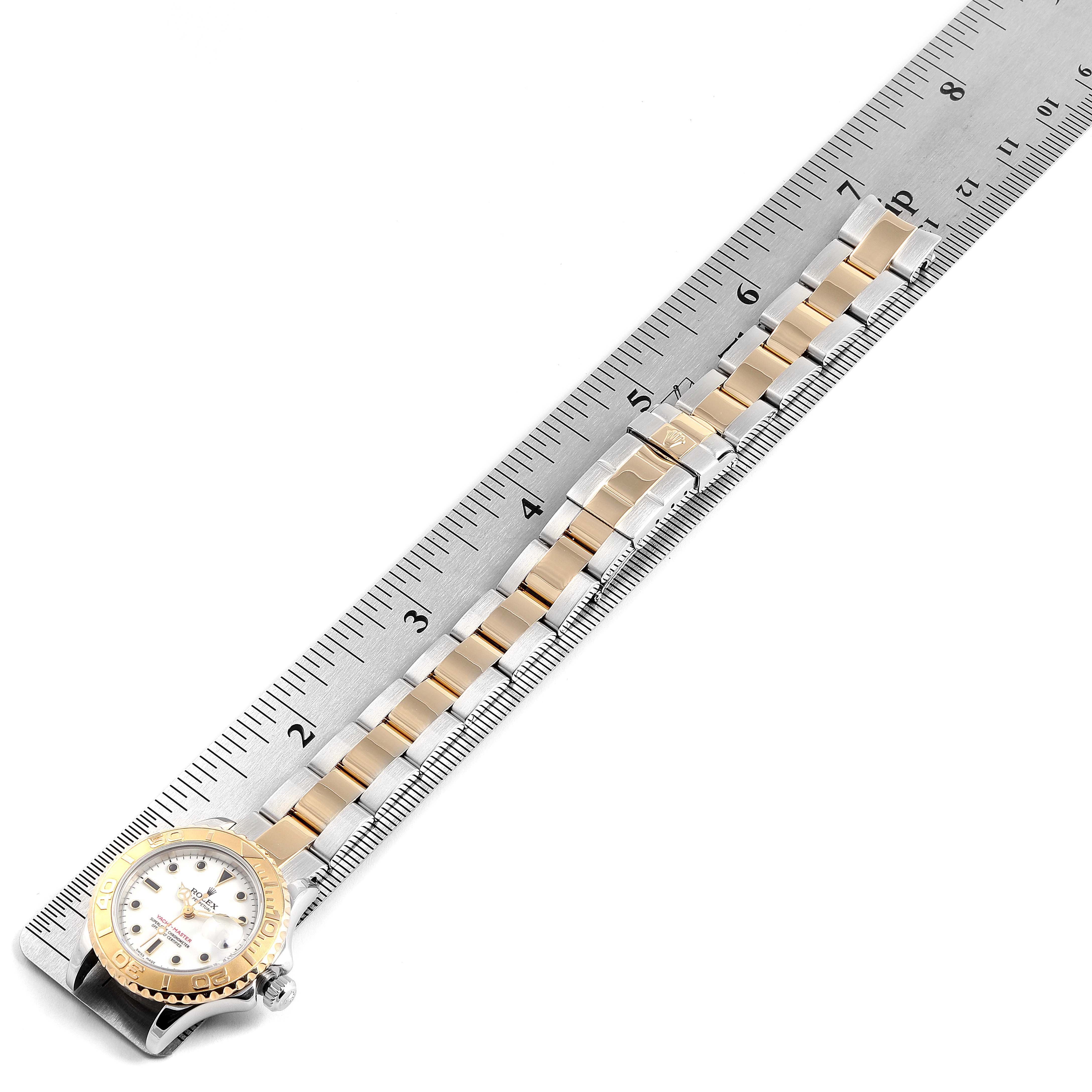 The Rolex Yacht-Master 169623 Women's Steel and Gold (two tone) White Dial 169623 Women's Steel and Gold (two tone) White Dial watch is shown from a top view with its bracelet and case aligned alongside a ruler.