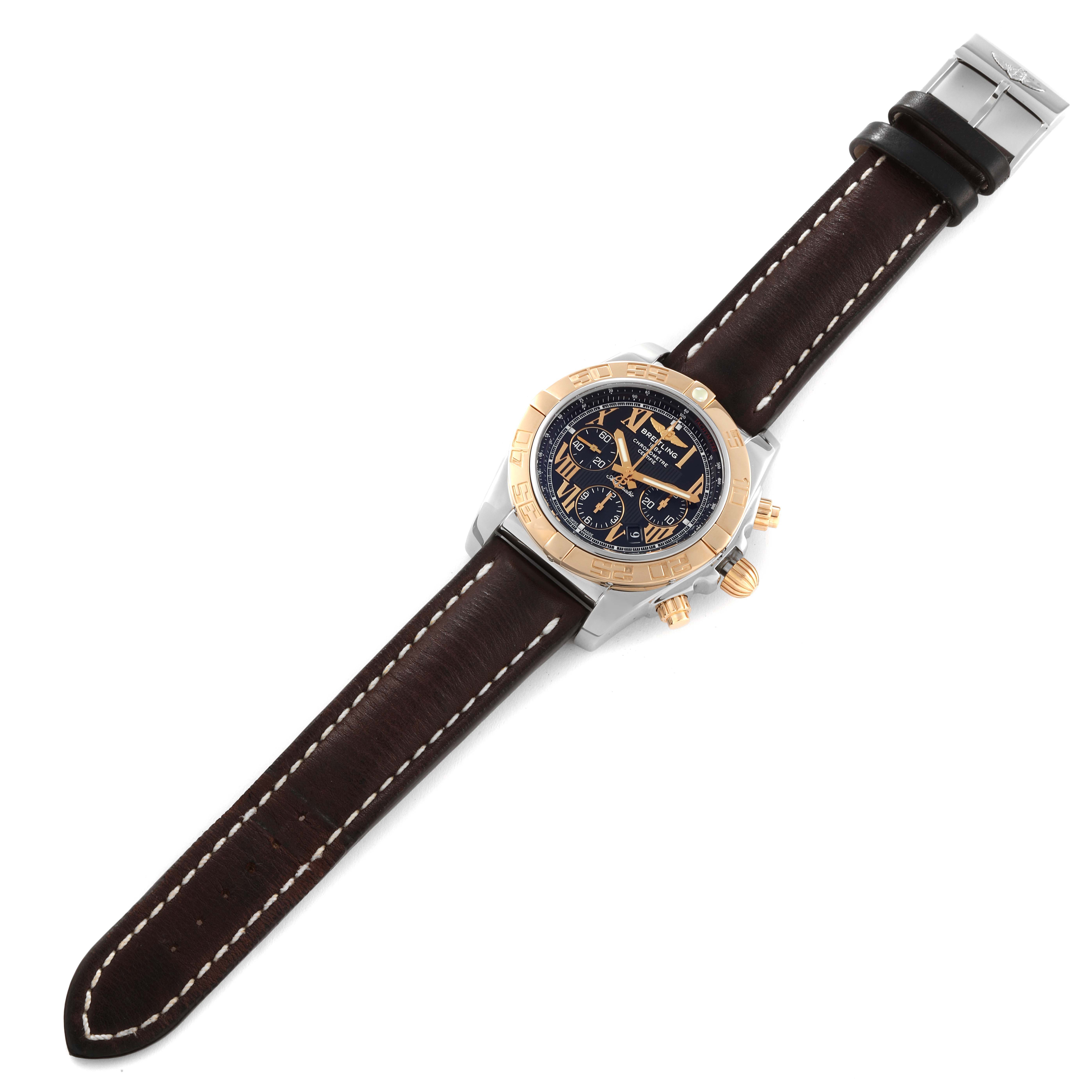 The Breitling Chronomat CB0110 Men's Steel and Gold (two tone) Black Dial CB0110 Men's Steel and Gold (two tone) Black Dial watch is shown from an angled top view, displaying its face, bezel, and leather strap.