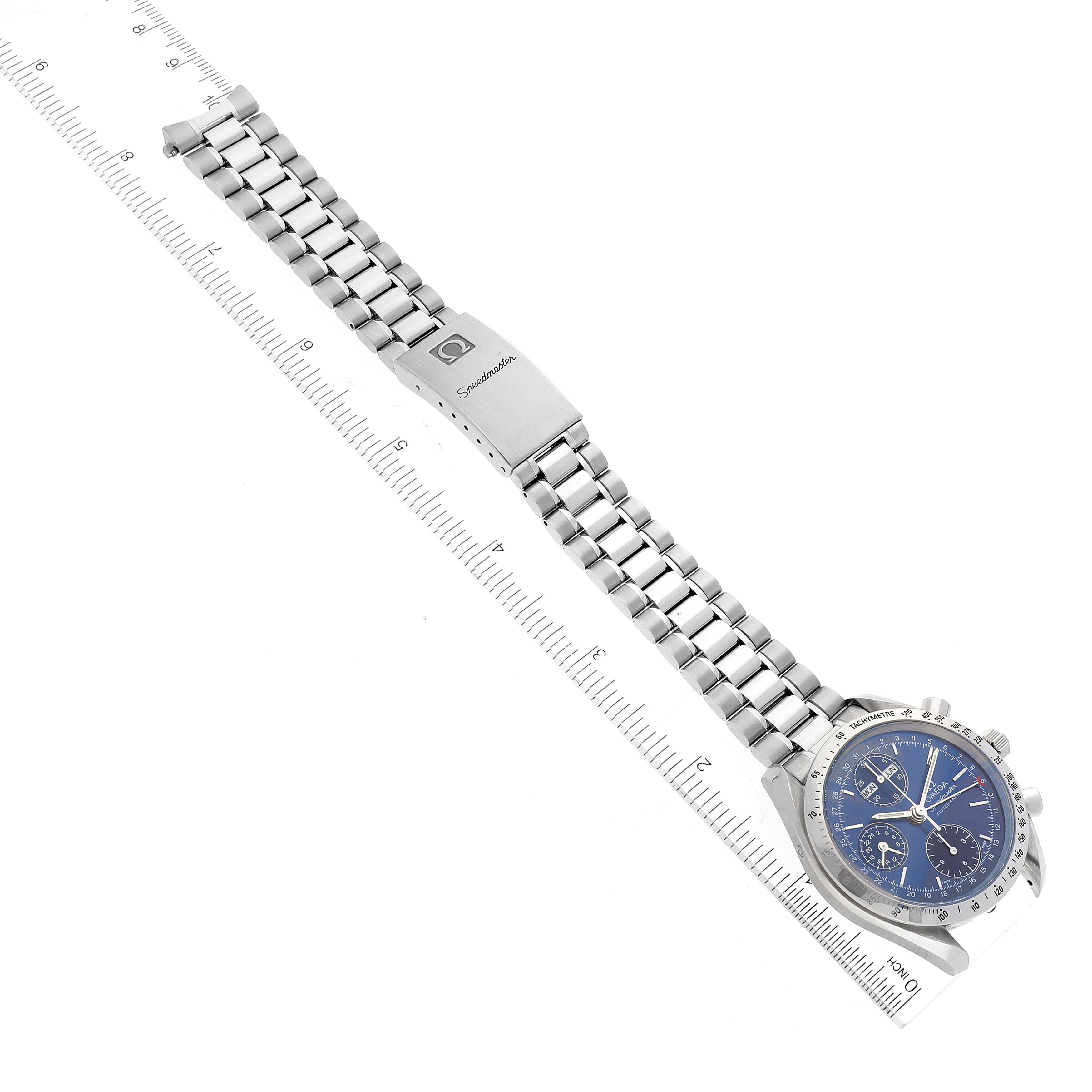 This image shows an Omega Speedmaster 3521.80.00 Men's Stainless Steel Blue Dial 3521.80.00 Men's Stainless Steel Blue Dial watch laid flat, displaying its face, bezel, and bracelet next to a ruler for scale.