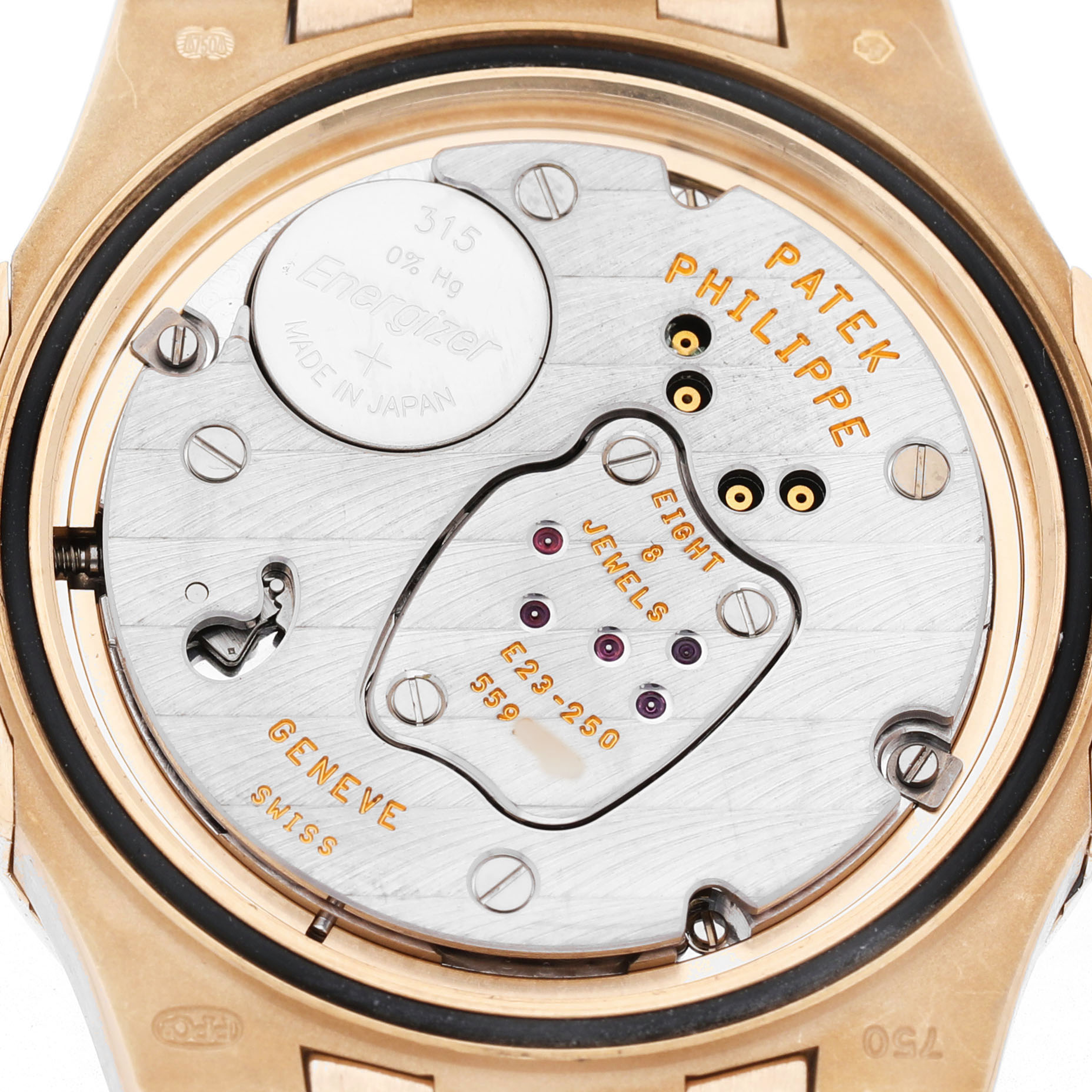 The image shows the back view of a Patek Philippe Nautilus 7011/1R-010 Women's Rose Gold Grey Dial watch, focusing on its movement and parts, including a battery.