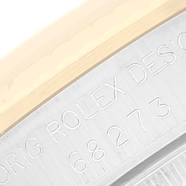 This close-up image shows the engraved model number and part of the bezel of a Rolex Mid-Size 68273 Women's Steel and Gold (two tone) Black Dial 68273 Women's Steel and Gold (two tone) Black Dial watch.