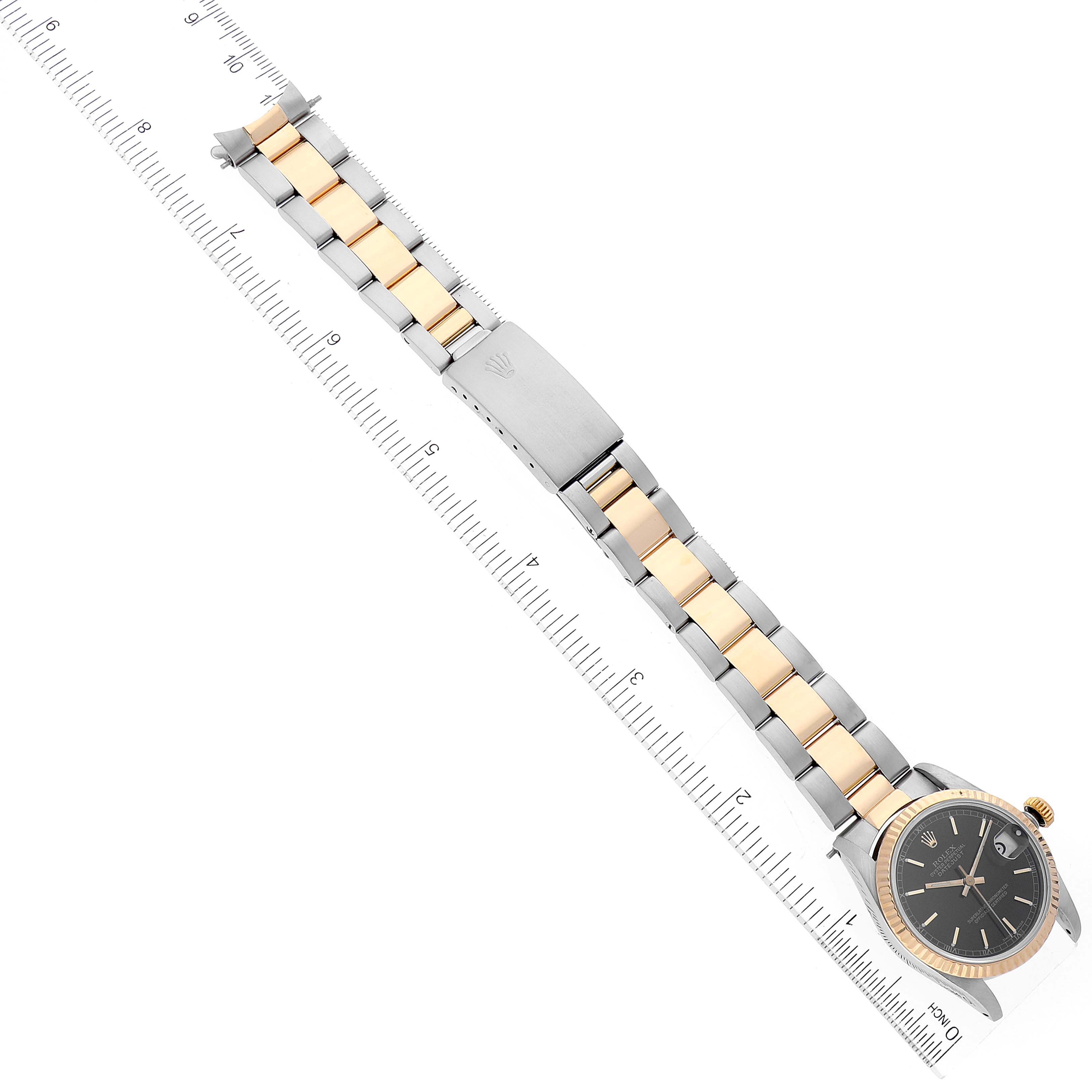 The Rolex Mid-Size 68273 Women's Steel and Gold (two tone) Black Dial 68273 Women's Steel and Gold (two tone) Black Dial watch is shown parallel to a ruler, displaying its two-tone bracelet and black dial with partial face view.