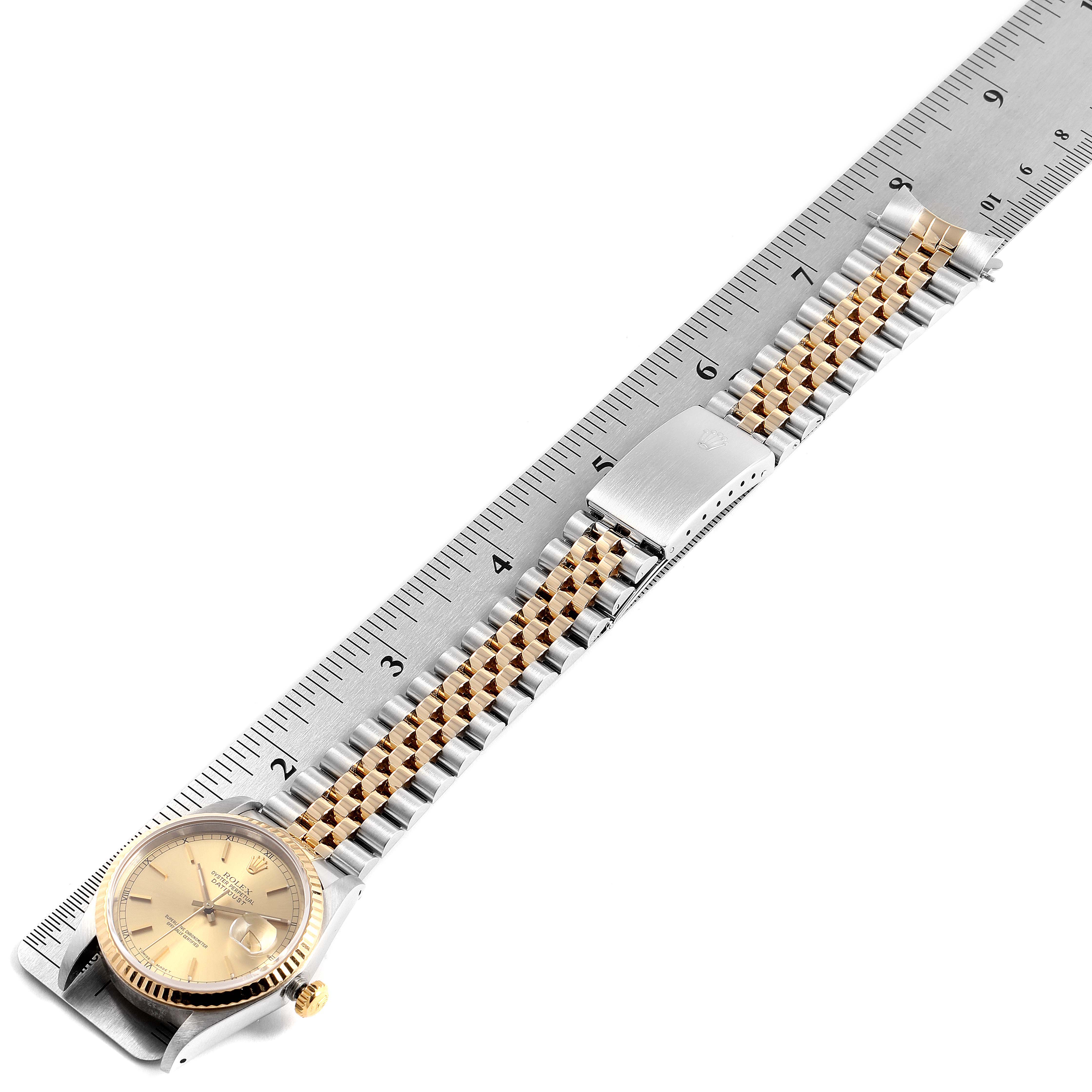 The Rolex Datejust 16233 Men
s Steel and Gold (two tone) Champagne Dial 16233 Men
s Steel and Gold (two tone) Champagne Dial watch is shown from an overhead angle, fully extended, placed next to a ruler.
