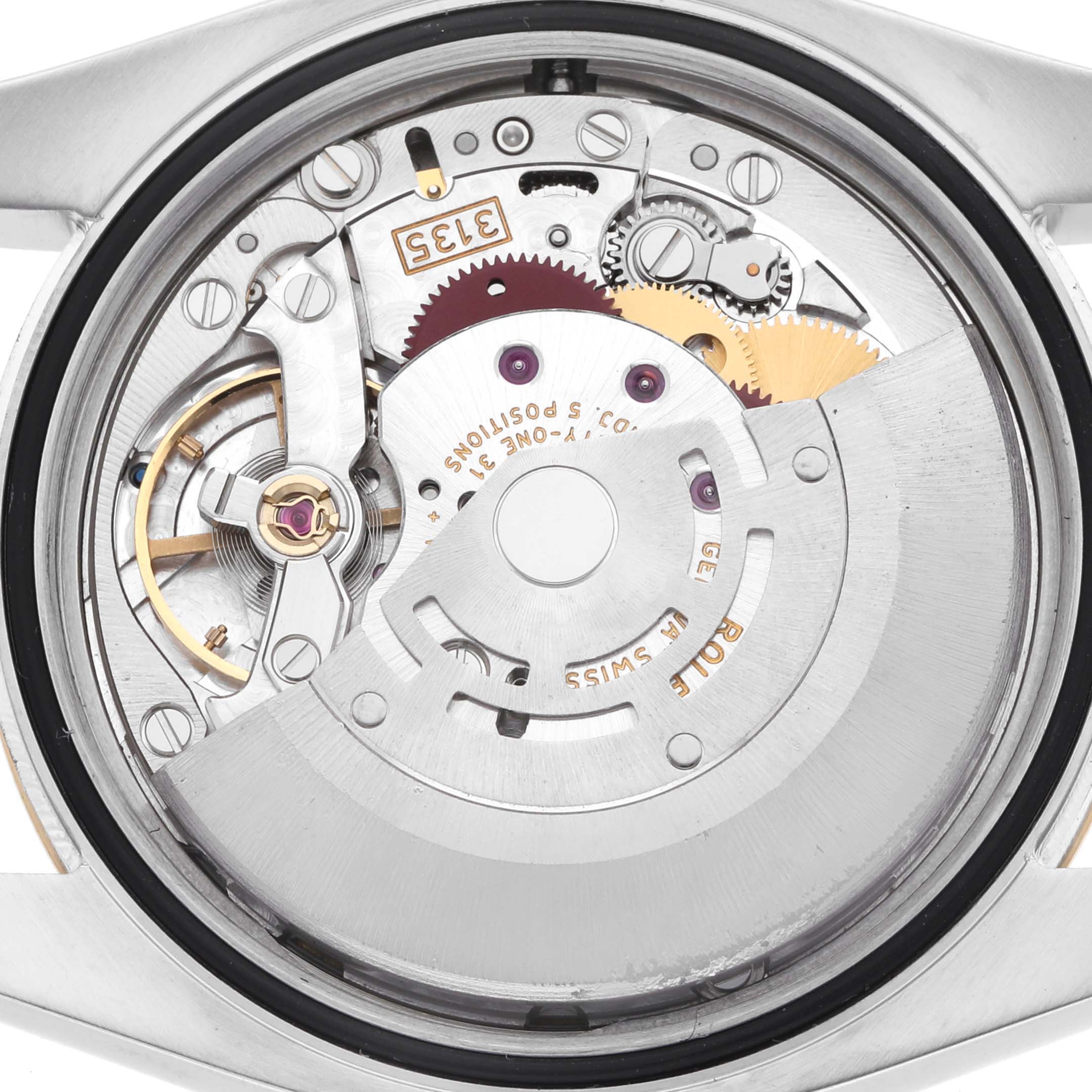 The image shows a close-up of the Rolex Datejust 116233 Men
s Steel and Gold (two tone) White Dial watch movement from a back view angle, revealing the intricate gears and rotor.