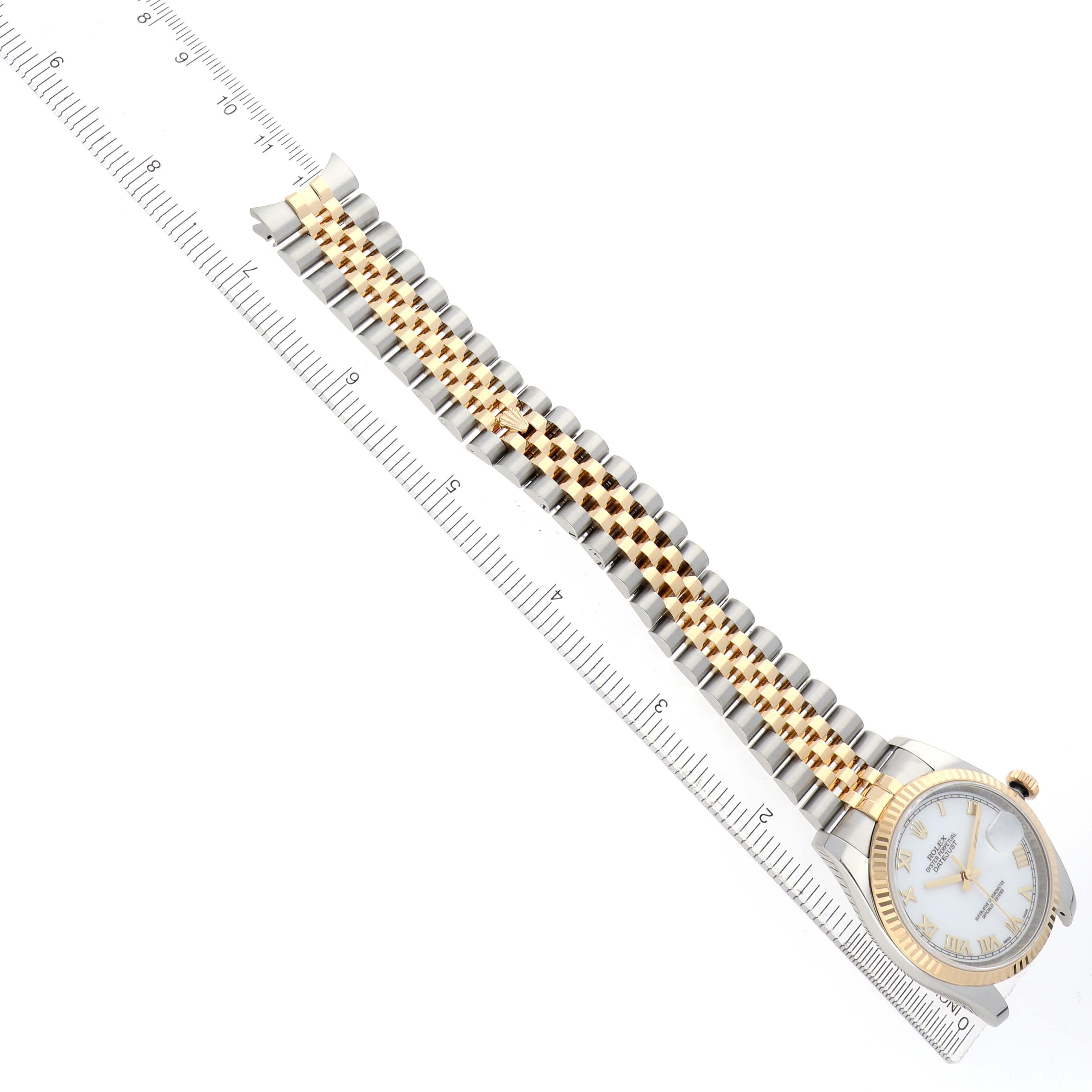 The Rolex Datejust 116233 Men
s Steel and Gold (two tone) White Dial watch is shown from a top-down angle with the face, bezel, and full bracelet visible, alongside a ruler for scale.
