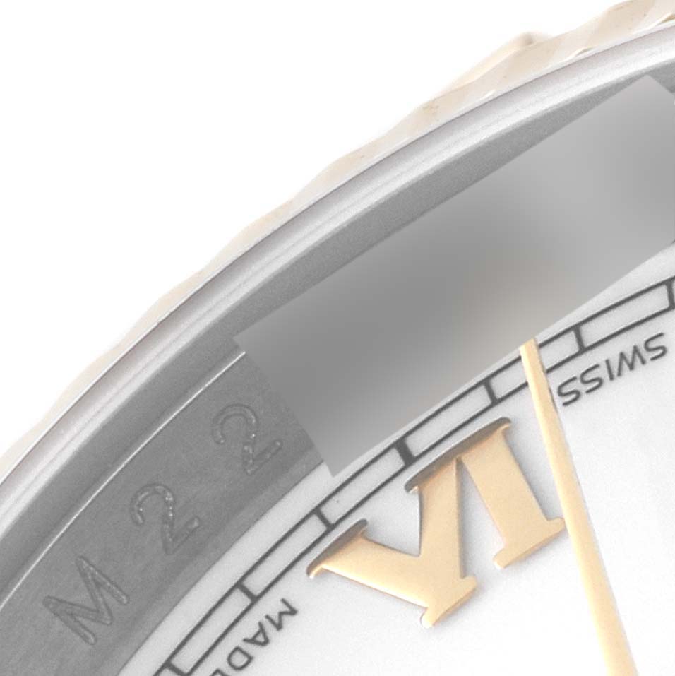 This close-up image of the Rolex Datejust 116233 Men's Steel and Gold (two tone) White Dial 116233 Men's Steel and Gold (two tone) White Dial watch shows a portion of the dial with a Roman numeral VI and part of the outer bezel.
