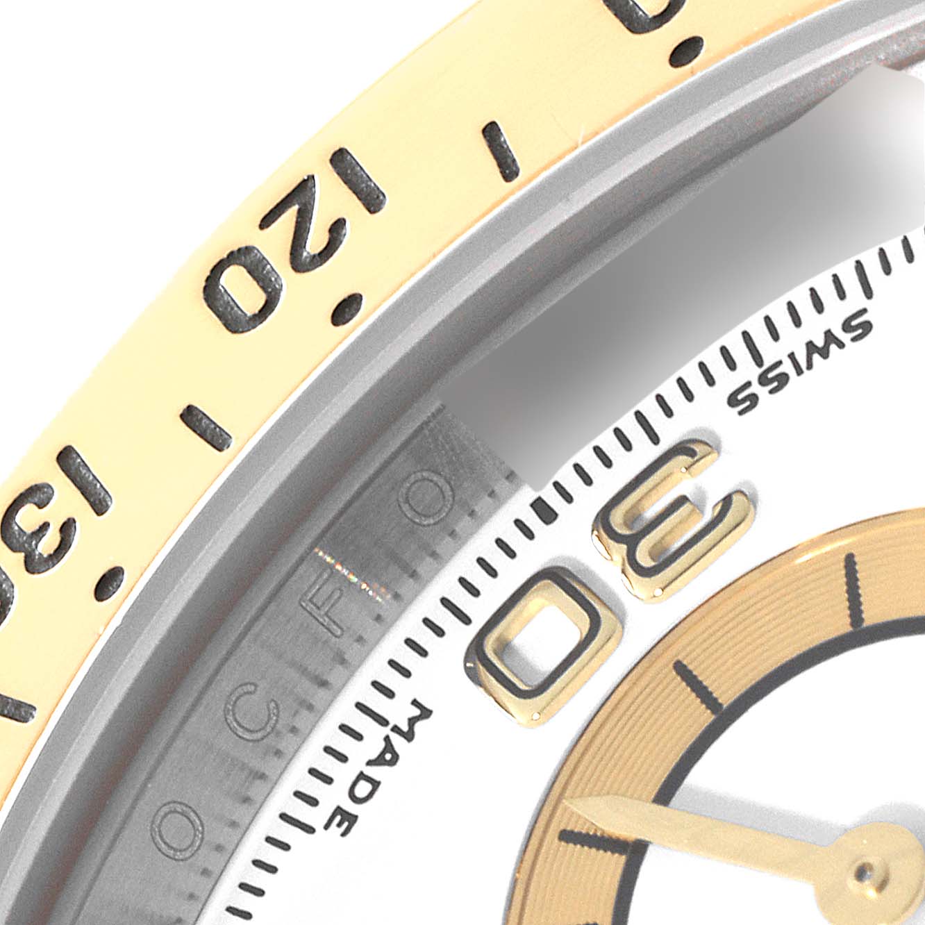 This close-up of a Rolex Daytona 116523 Men
s Steel and Gold (two tone) White Dial 116523 Men
s Steel and Gold (two tone) White Dial watch shows its bezel with minute markers, part of the dial, and hour markers.