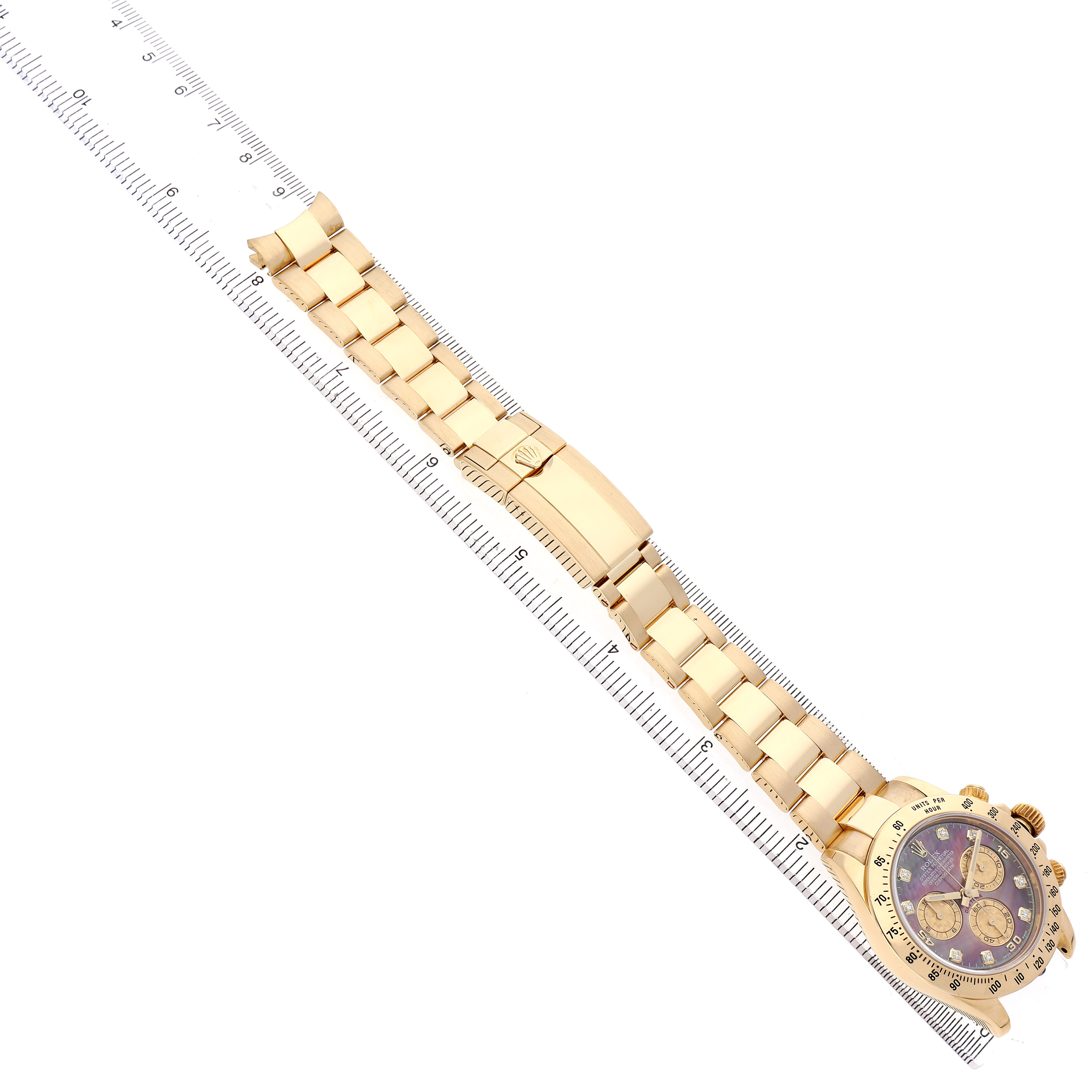 The Rolex Daytona 116528 Men's Yellow Gold Mother of Pearl Dial watch is shown at a diagonal angle, displaying the full bracelet and face alongside a ruler for scale.