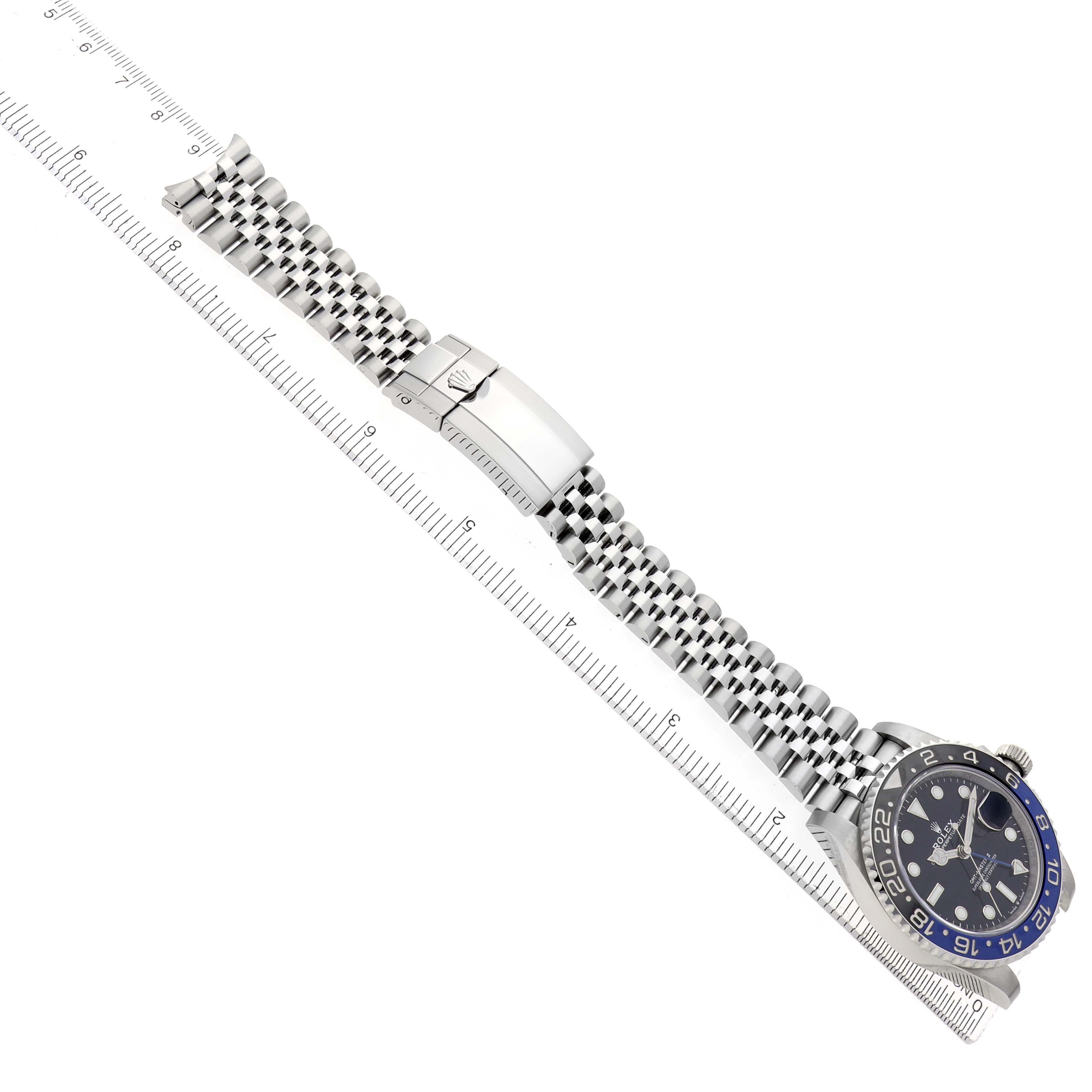 The Rolex GMT-Master 126710 Men
s Stainless Steel Black Dial watch is shown at an angle displaying the face, bezel, bracelet, and clasp with a measuring ruler alongside.